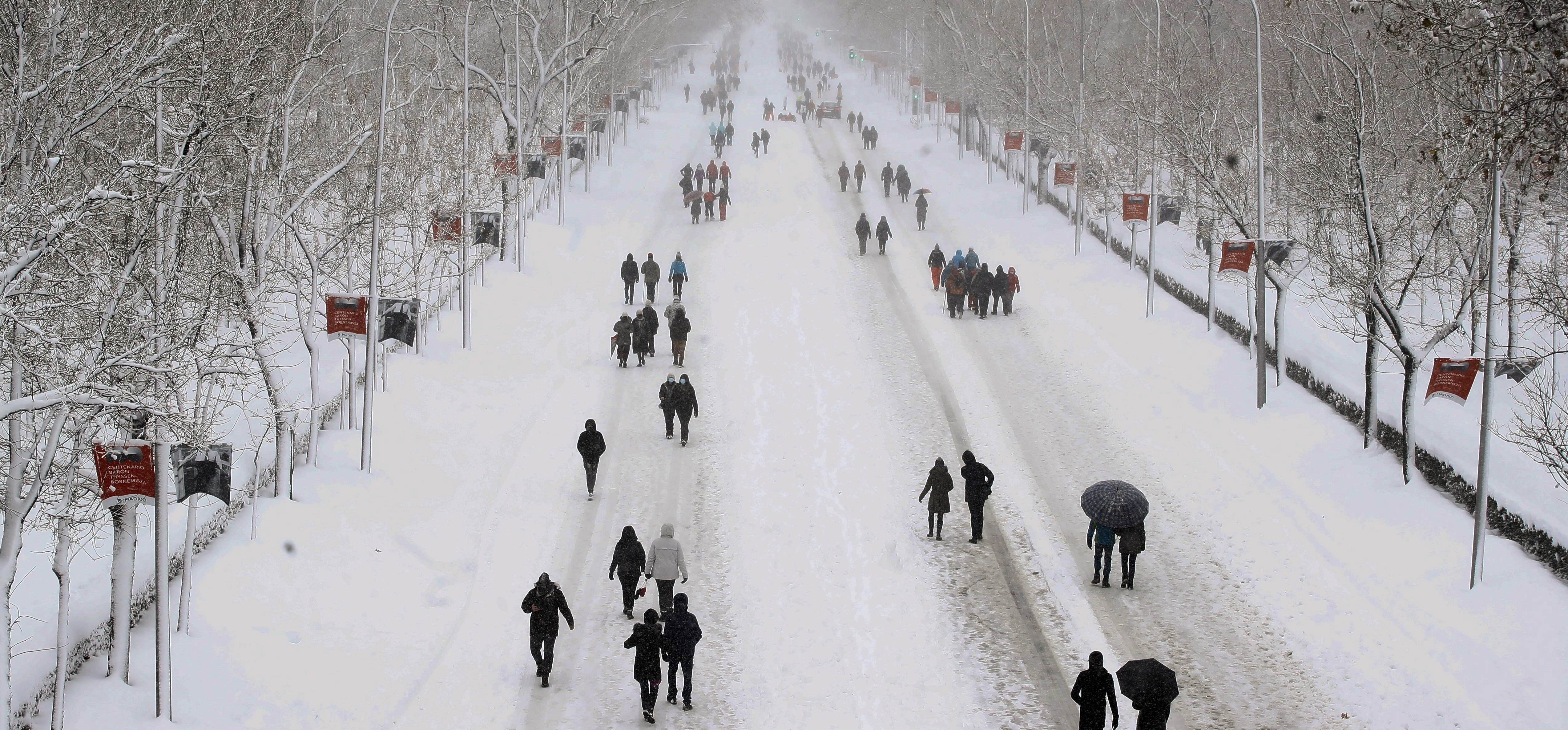 epa08928874 People walk along Castellana Avenue during the snowfall in Madrid, Spain, 09 January 2021. Storm Filomena brought the heaviest snowfall in decades.  EPA-EFE/Ballesteros