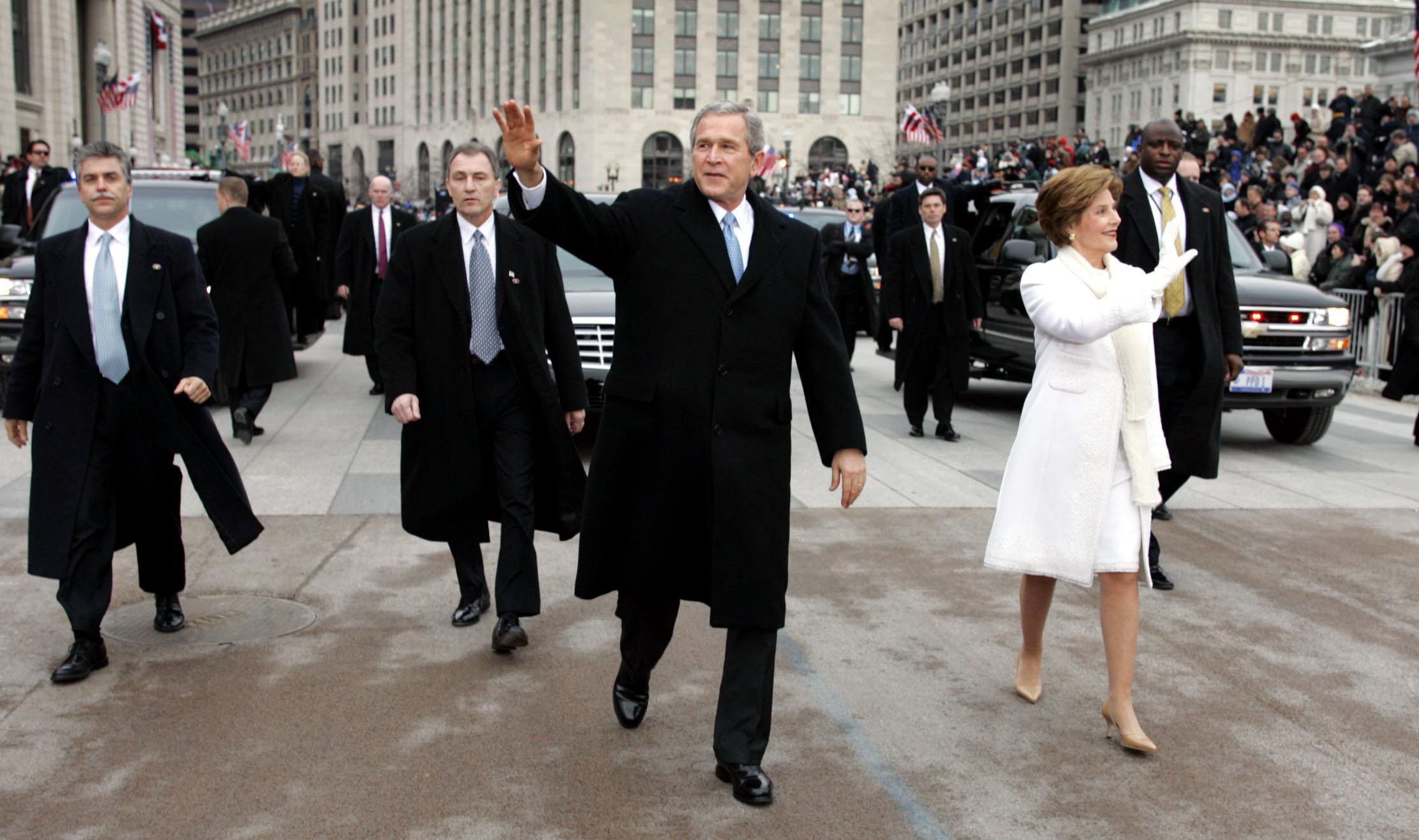 retro United States President George W. Bush (C) walks with his wife Laura (R) and Secret Service Agents during a parade along Pennsylvania Ave in front of the White House following his inauguration in Washington