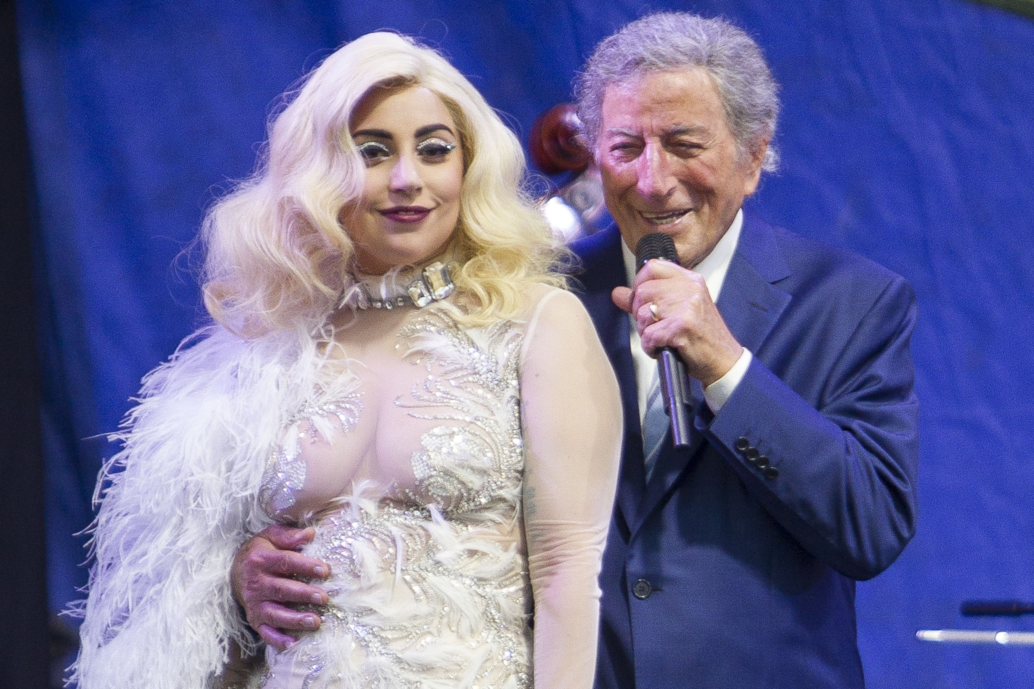 Lady Gaga wears a semi-sheer gown with white feather detailing while performing with Tony Bennett at the New Orleans Jazz Fest