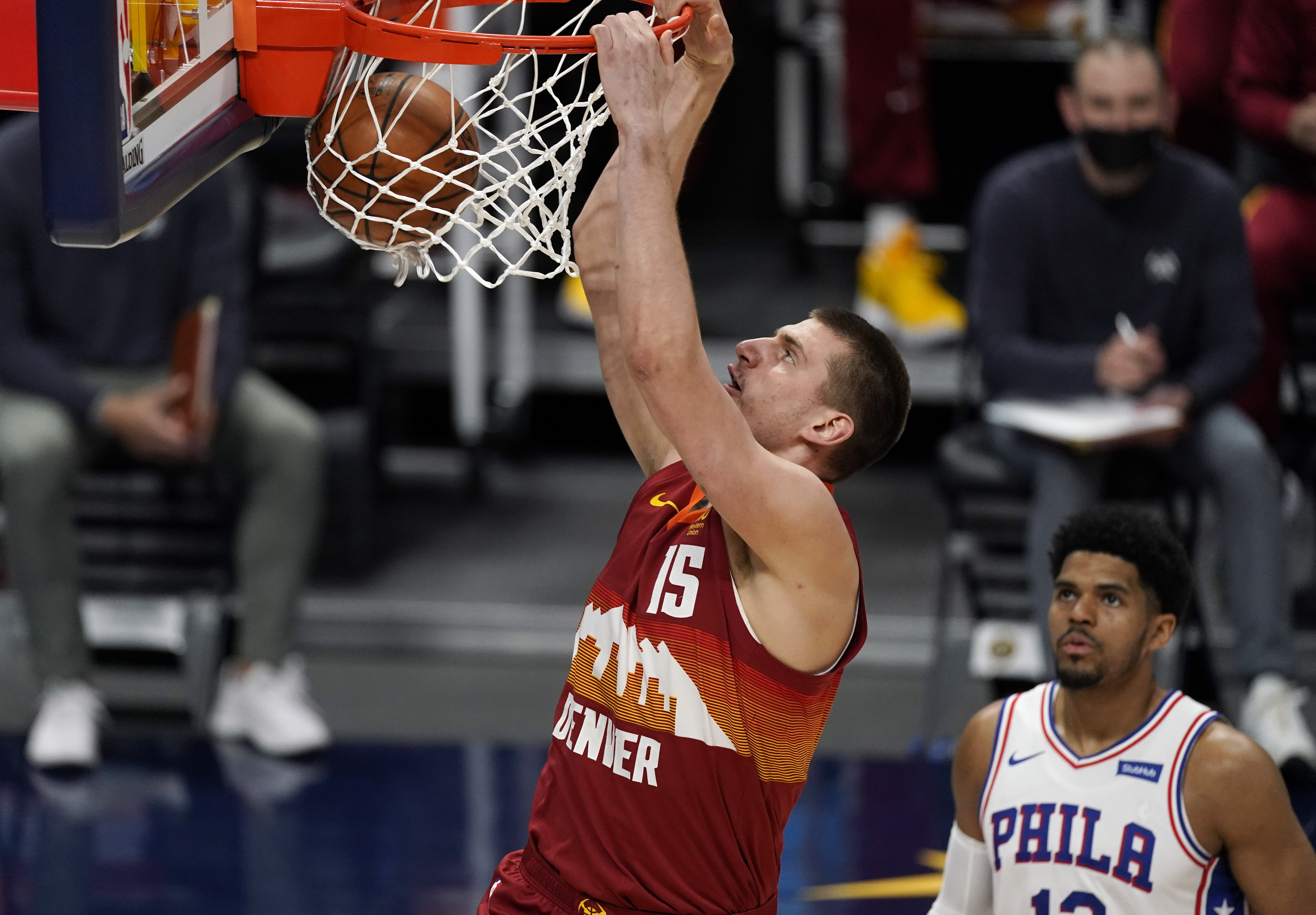 Denver Nuggets center Nikola Jokic, left, dunks the ball for a basket as Philadelphia 76ers forward Tobias Harris looks on in the first half of an NBA basketball game Tuesday, March 30, 2021, in Denver. (AP Photo/David Zalubowski)