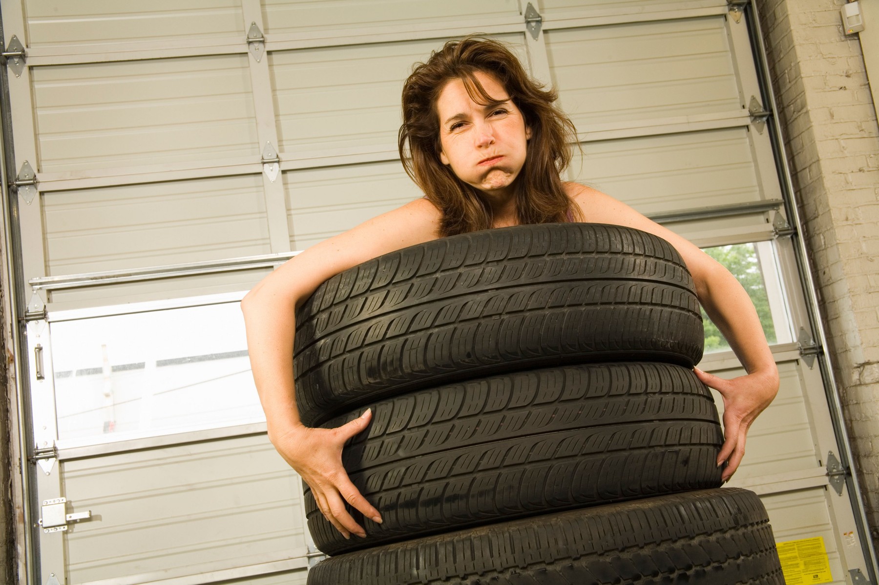 Nude woman standing in stack of tires