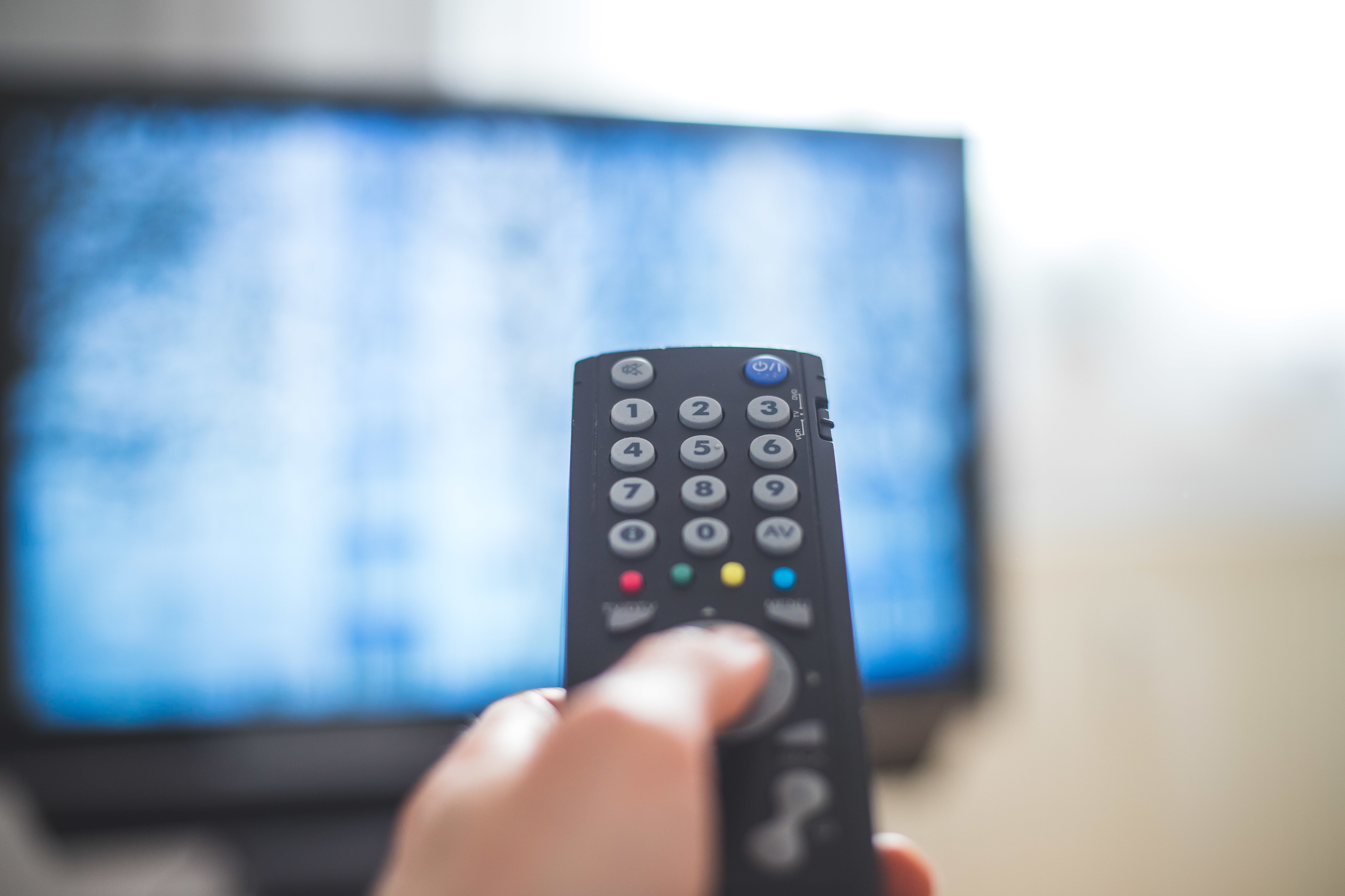 Holding a TV remote control in the hand,  foreground,  tv in the blurry background. Streaming.,Image: 589376110, License: Royalty-free, Restrictions: , Model Release: no, Credit line: Patrick Daxenbichler / Panthermedia / Profimedia