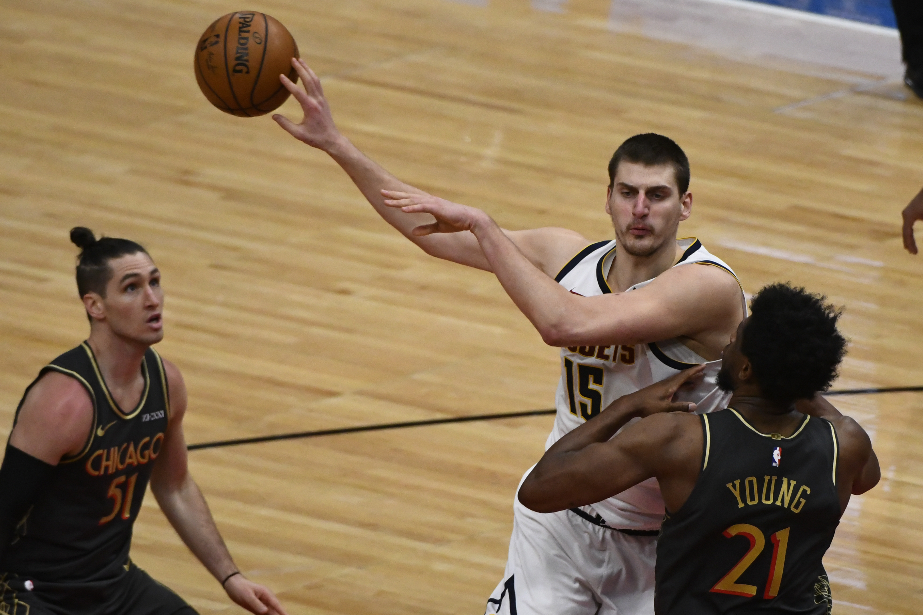 Denver Nuggets center Nikola Jokic (15) passes between Chicago Bulls guard Ryan Arcidiacono (51) and forward Thaddeus Young (21) during the second half of an NBA basketball game Monday, March 1, 2021, in Chicago. (AP Photo/Matt Marton)