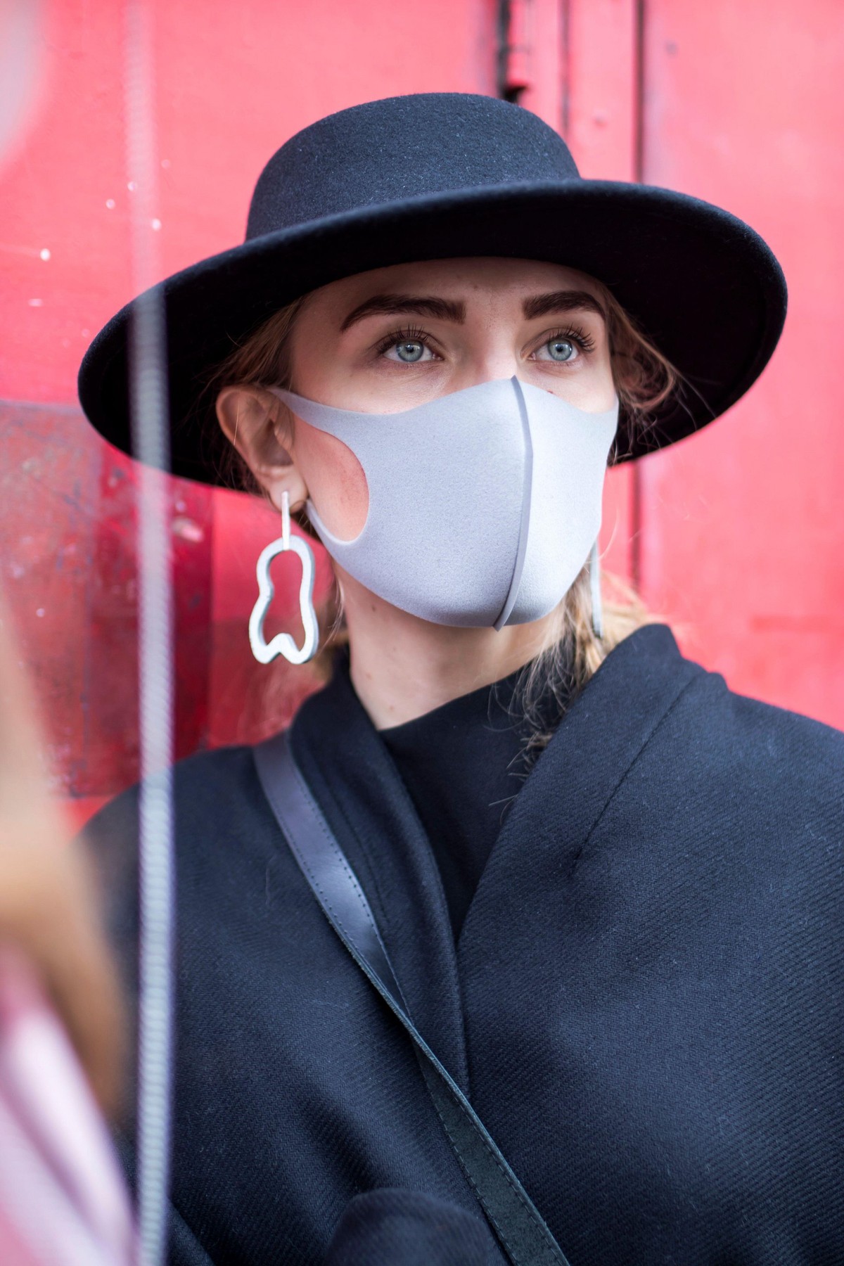 London, UK - 10 February, 2020 People wear mask for protection. Street style. Stylish woman in black dress, coat and a wide-brimmed hat wears a beige
