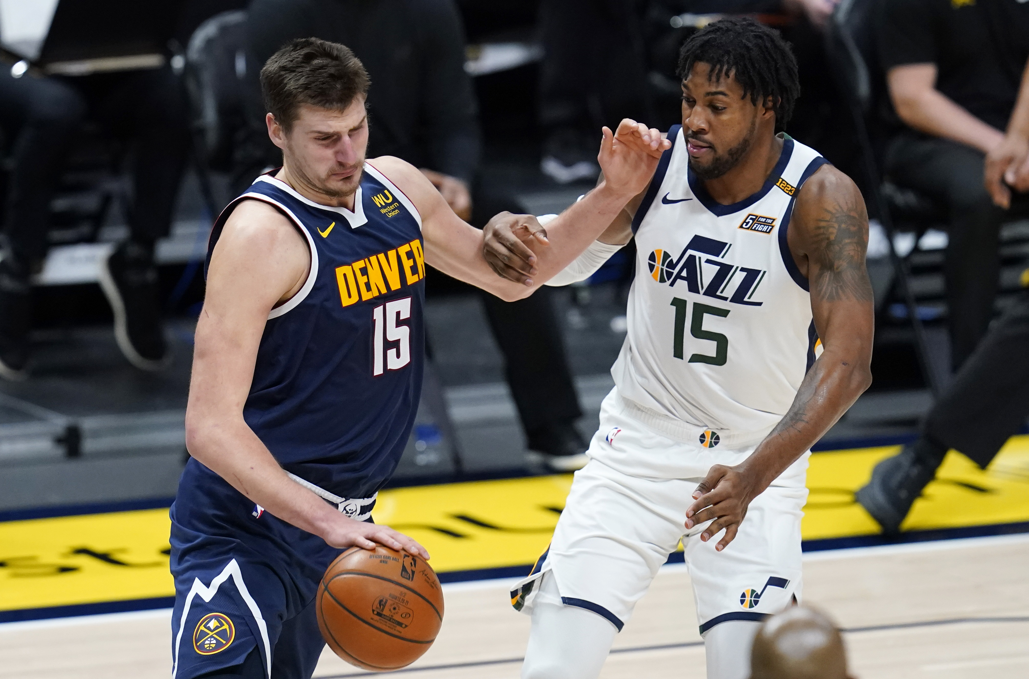 Denver Nuggets center Nikola Jokic, left, drives past Utah Jazz center Derrick Favors in the second half of an NBA basketball game Sunday, Jan. 17, 2021, in Denver. (AP Photo/David Zalubowski)