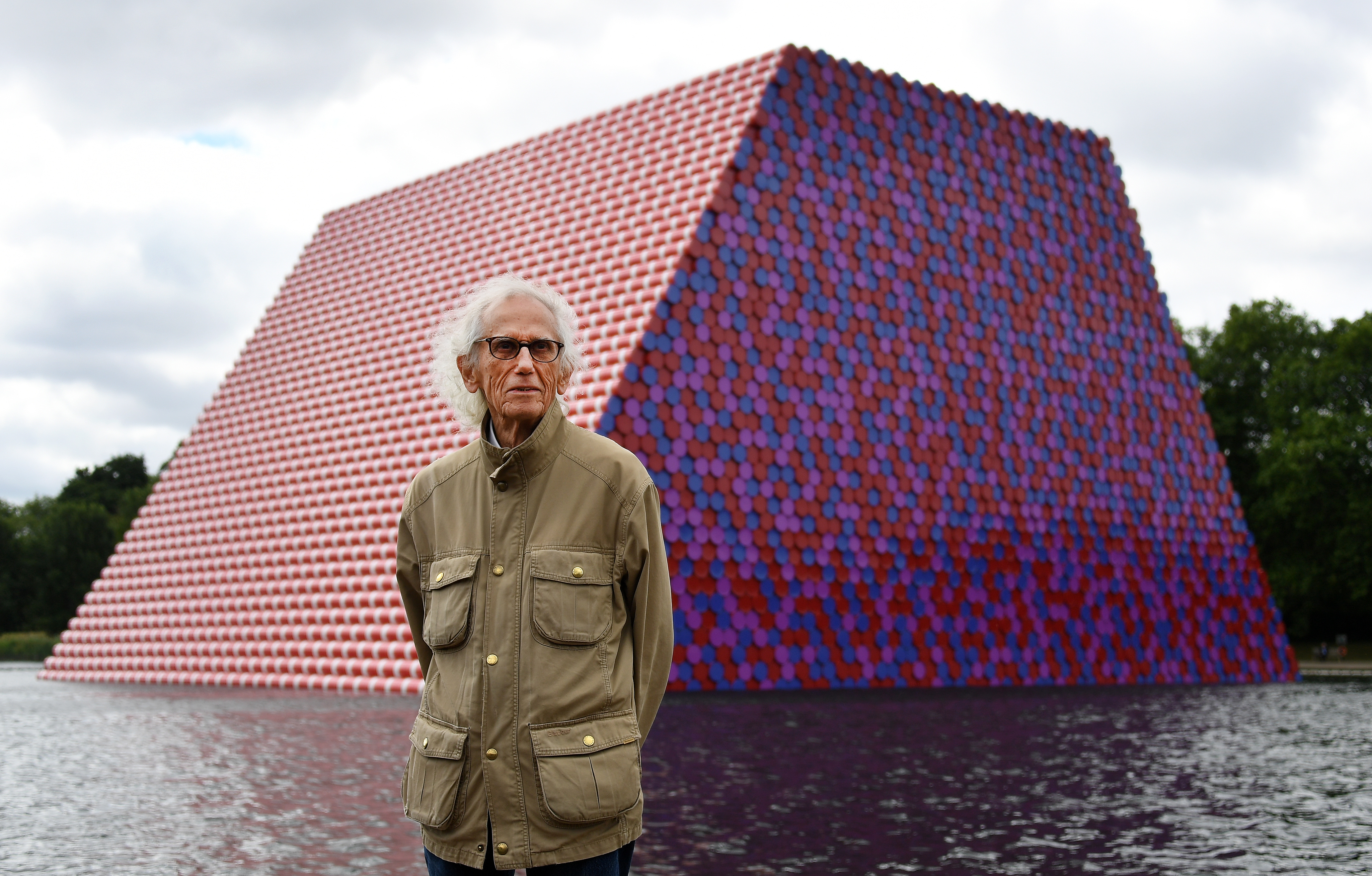epa08776945 YEARENDER 2020 
FAREWELLS

Bulgarian artist Christo stands in front of his artwork 'Mastaba' built on The Serpentine lake in London, Britain, 18 June 2018. Christo has died aged 84 on 31 May 2020 in New York.  EPA-EFE/ANDY RAIN