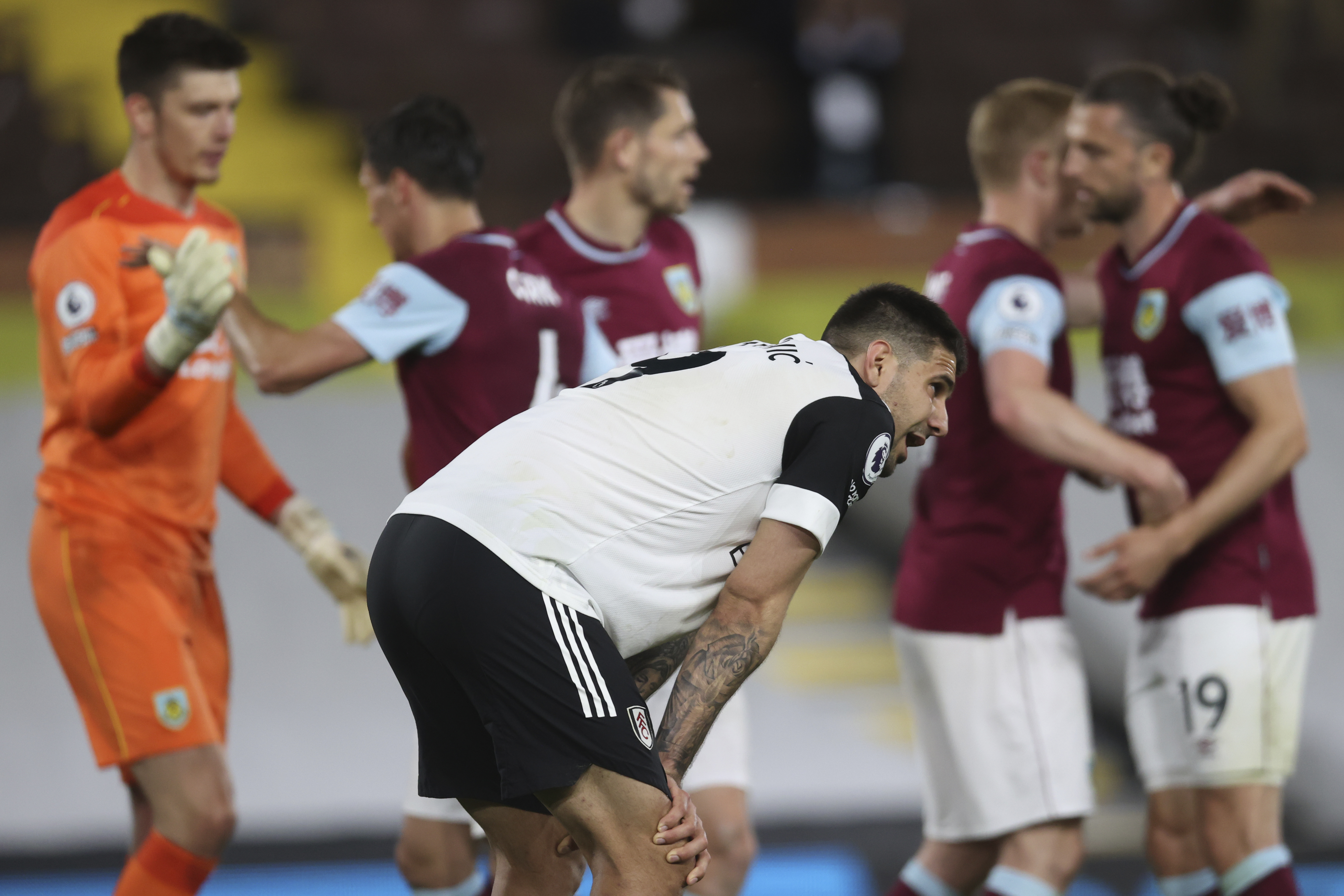 Fulham's Aleksandar Mitrovic, center, is dejected as Burnley players celebrate at the end of the English Premier League soccer match between Fulham and Burnley at the Craven Cottage Stadium in London, Monday, May 10, 2021. (Clive Rose/Pool via AP)