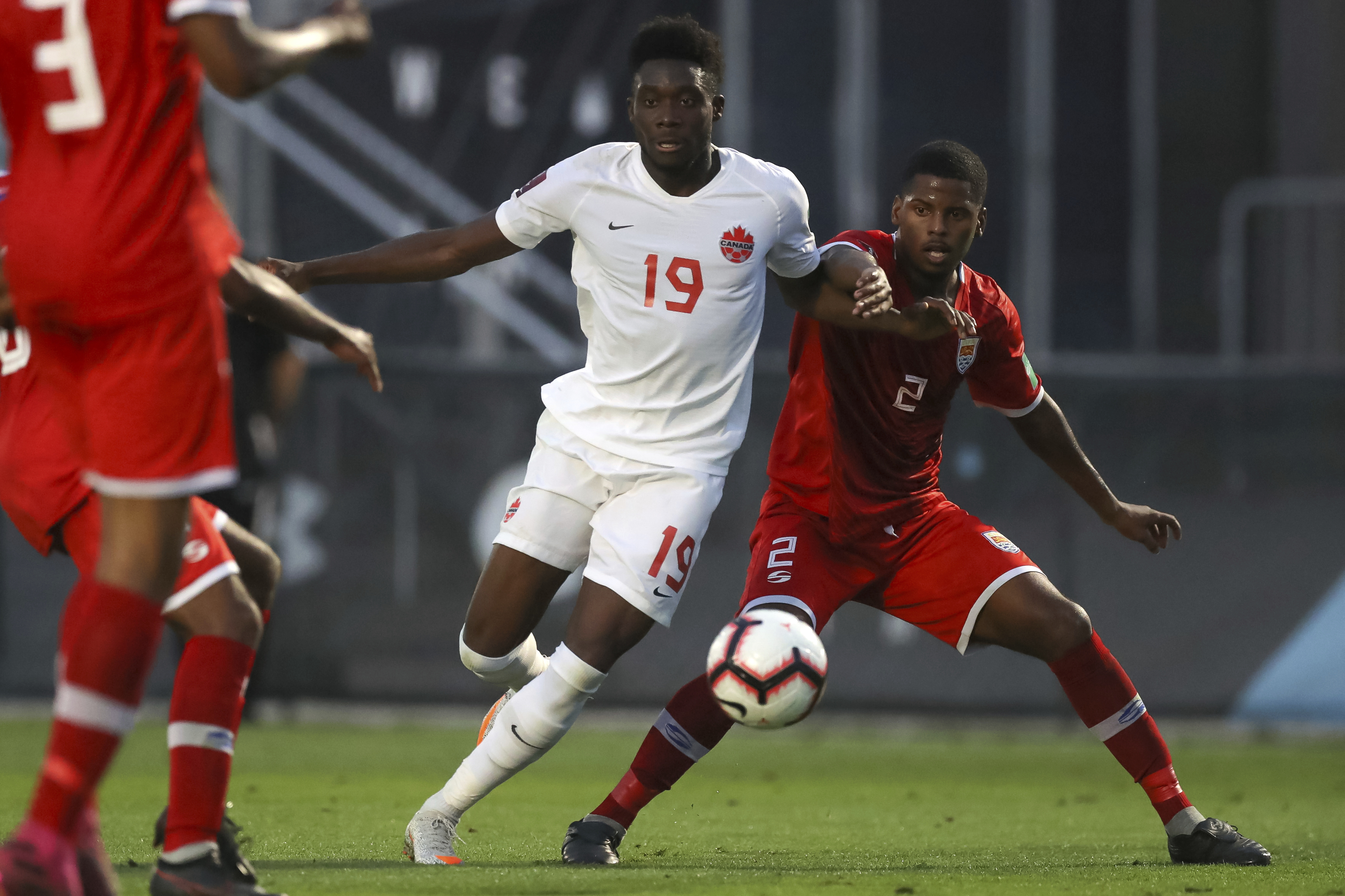 Canada's Alphonso Davies (19) breaks past Cayman Island defender Cameron Gray during the second half of a World Cup 2022 Group B qualifying soccer match Monday, March 29, 2021, in Bradenton, Fla. (AP Photo/Mike Carlson)