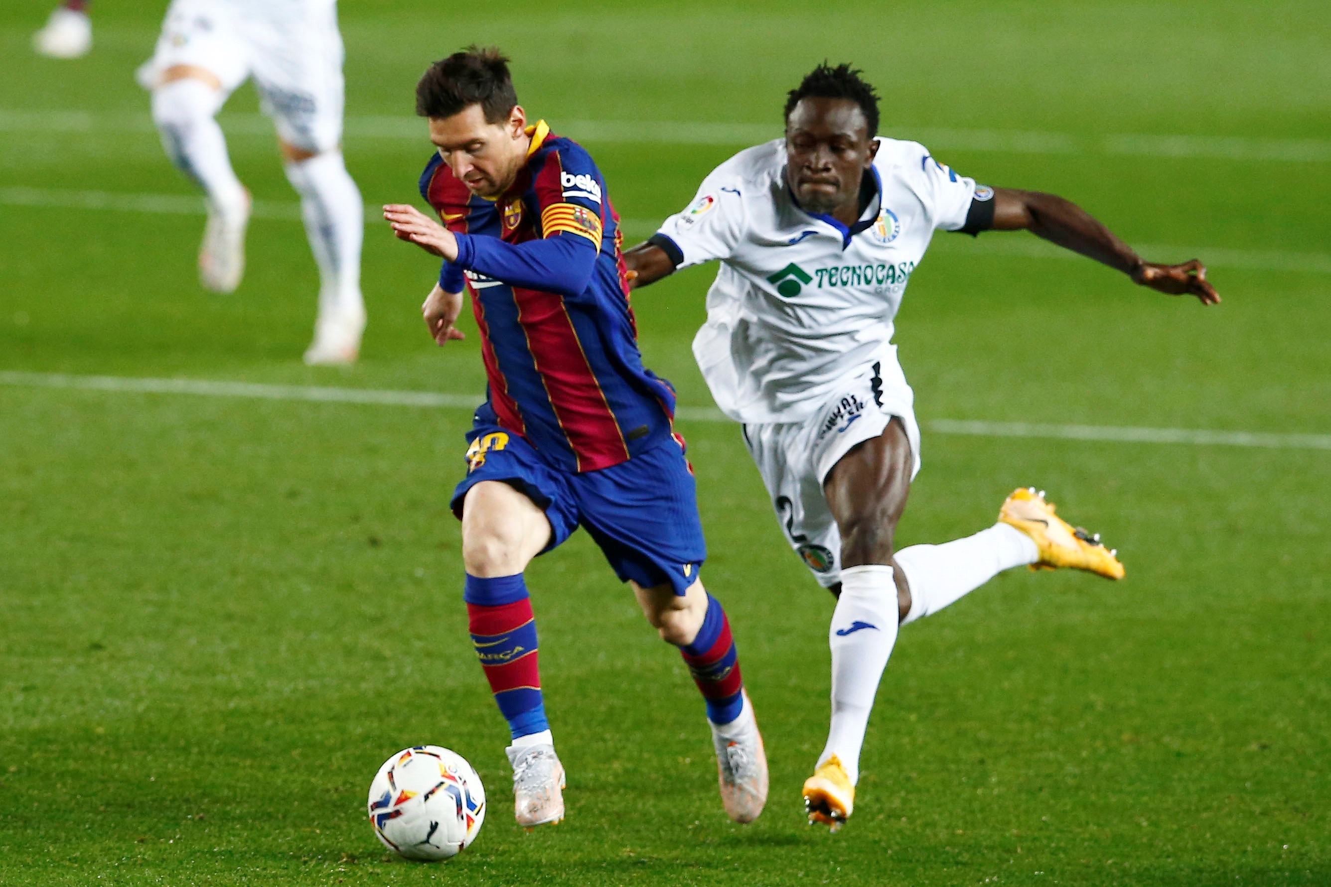 epaselect epa09153708 FC Barcelona's Lionel Messi (L) in action against Getafe's Djene Dakoman during a Spanish LaLiga soccer match between FC Barcelona and Getafe CF at Camp Nou stadium in Barcelona, Spain, 22 April 2021.  EPA-EFE/ENRIC FONTCUBERTA