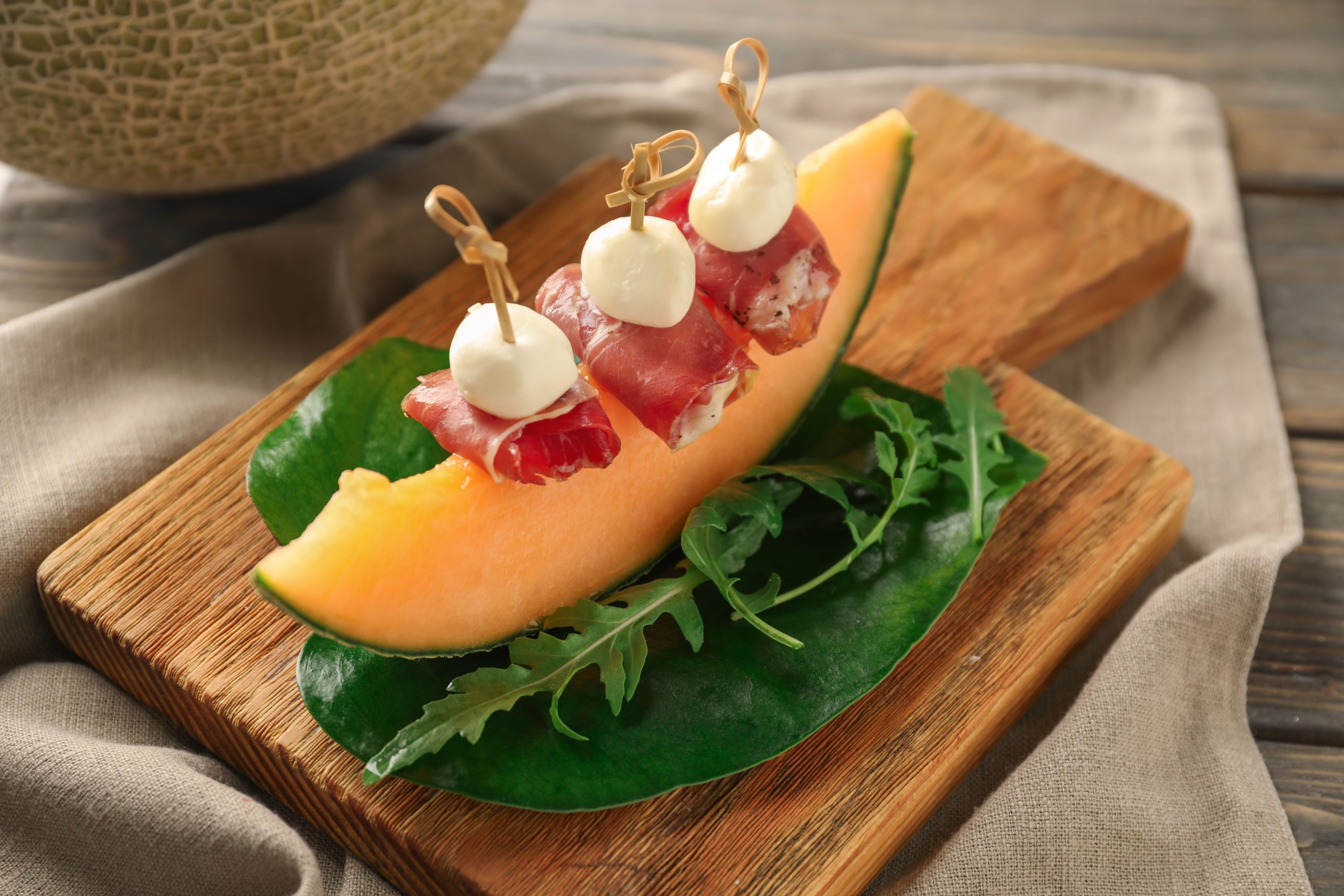 11.10. (b) Dinja sa prsutom  stock-photo-delicious-canape-with-melon-prosciutto-and-mozzarella-on-wooden-board-1193259103