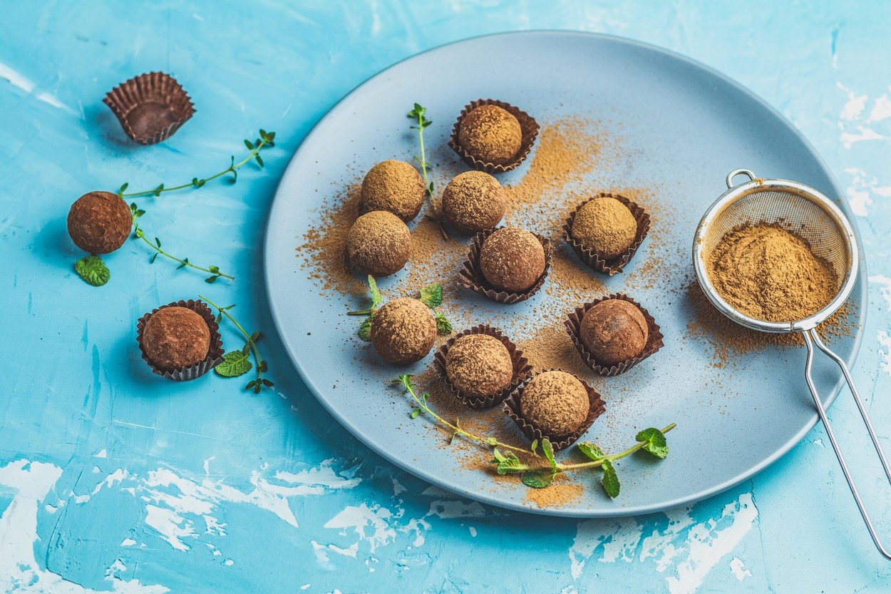 Cocoa balls, handmade chocolate balls cakes in a blue tray, sprinkled with cocoa powder, fresh mint and thyme on dark blue concrete surface background