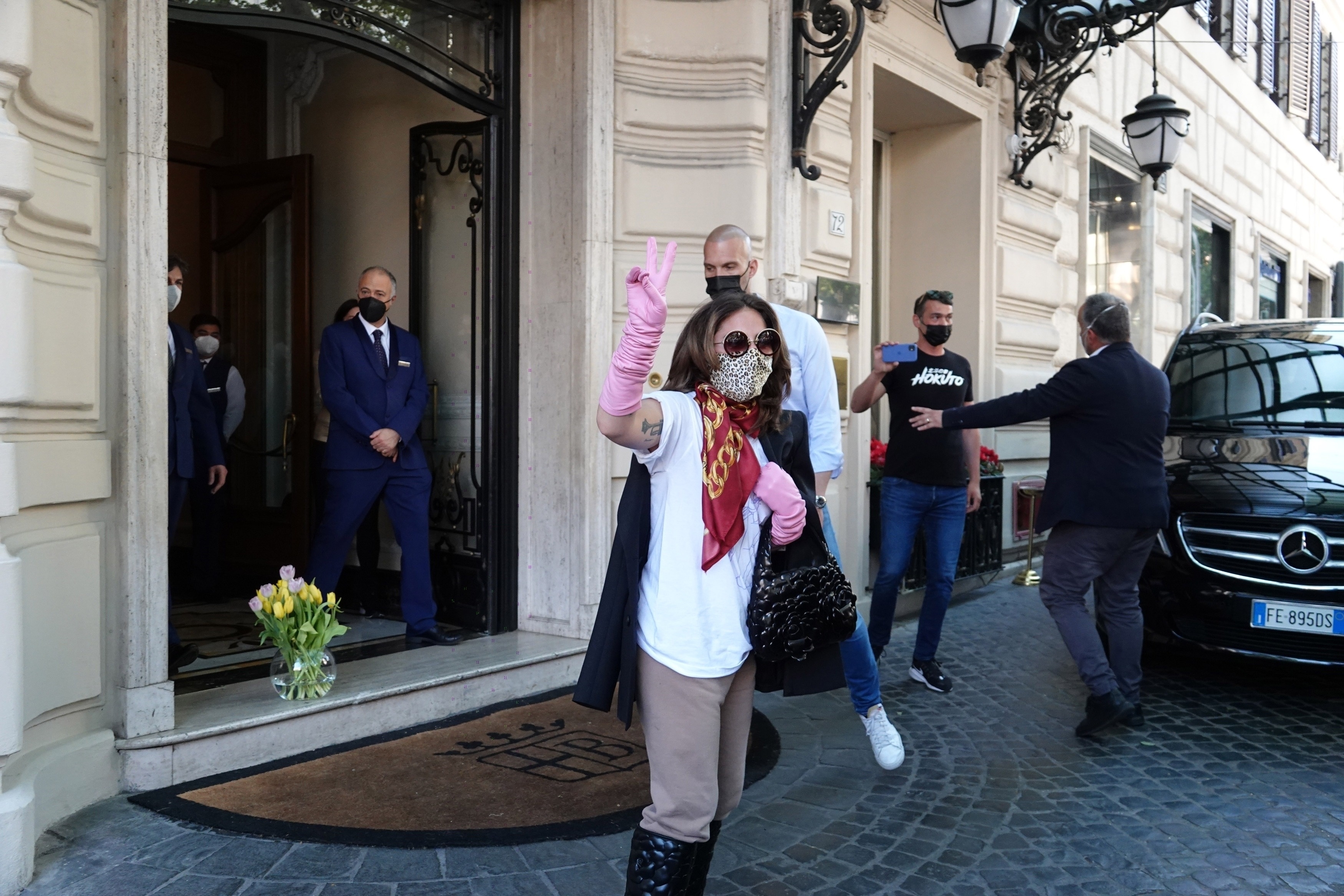 Lady Gaga throws flowers for fans as she leaves the hotel in Rome.