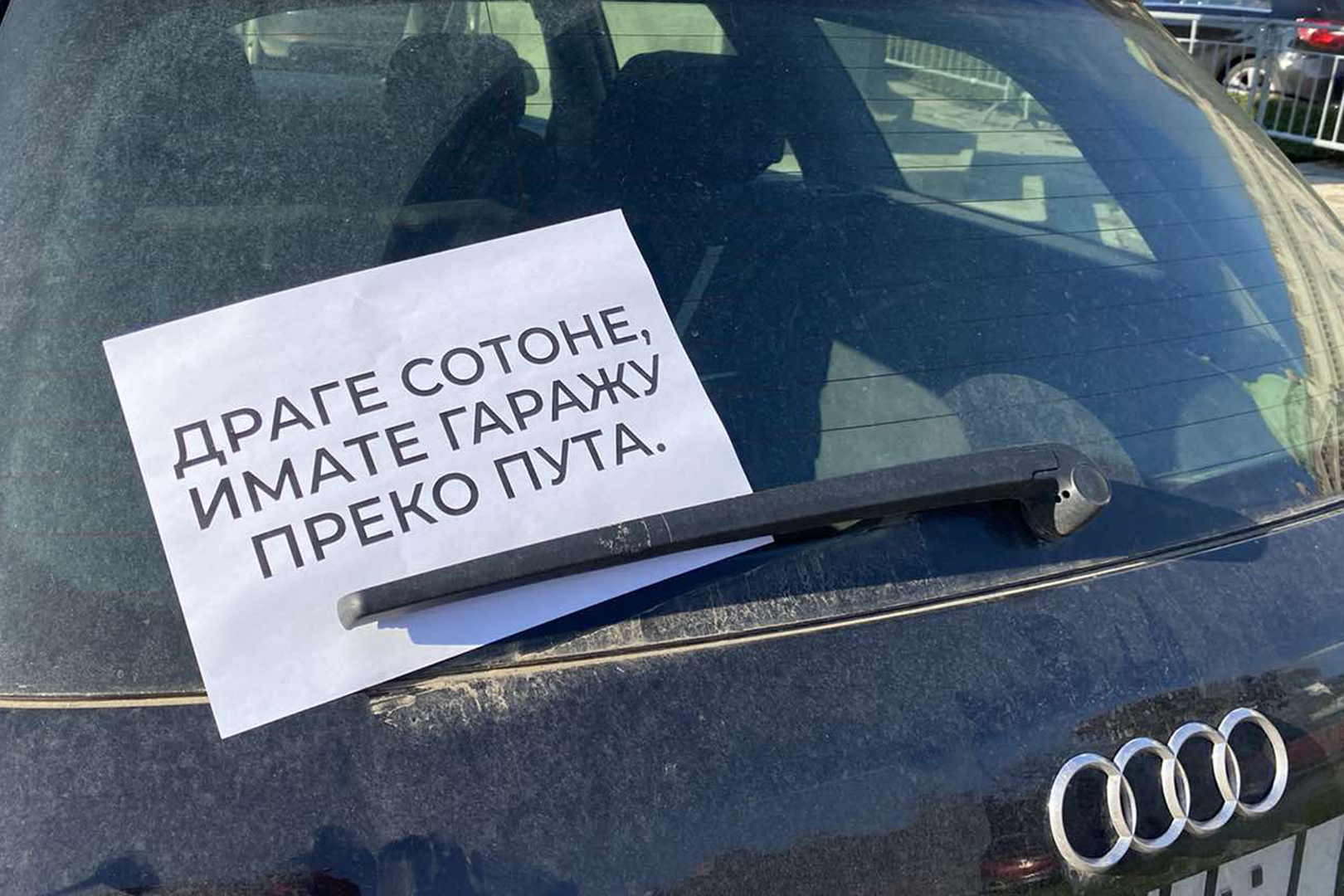 Bahato parkirani automobili ispred skupstine Srbije, na njih je neko nakacio papir sa natpisom " Drage sotone imate garazu preko puta "