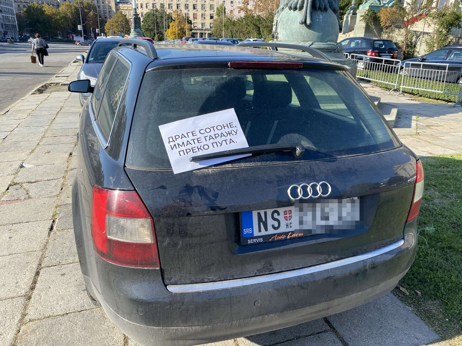 Bahato parkirani automobili ispred skupstine Srbije, na njih je neko nakacio papir sa natpisom " Drage sotone imate garazu preko puta "