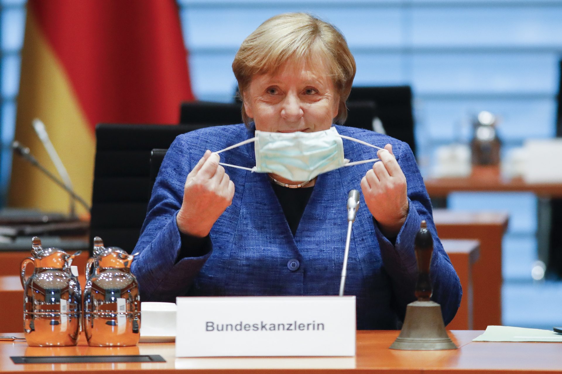 German Chancellor Angela Merkel takes down her face mask as she arrives for the weekly cabinet meeting of the German government at the chancellery in Berlin, Germany, Wednesday, Oct. 7, 2020. (AP Photo/Markus Schreiber, Pool)