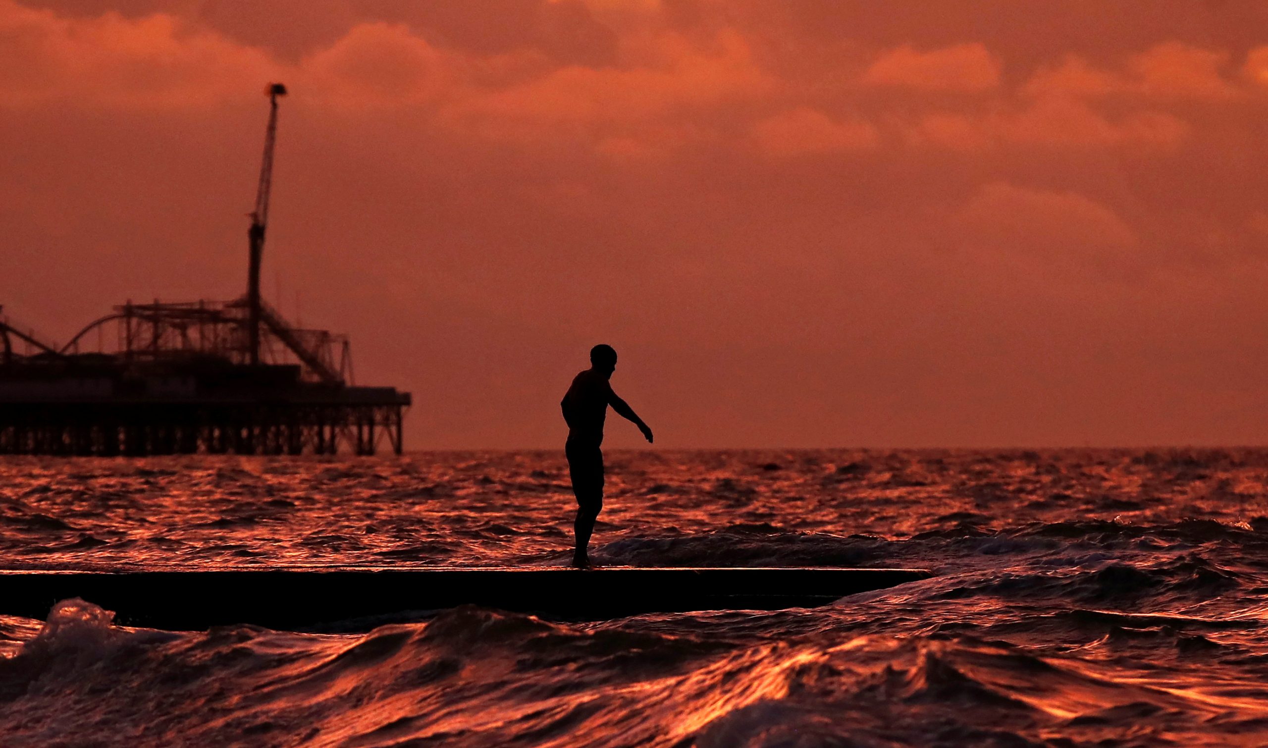 A man goes for a swim in the sea at sunrise in Brighton, Britain, November 11, 2020.  REUTERS/Peter Cziborra