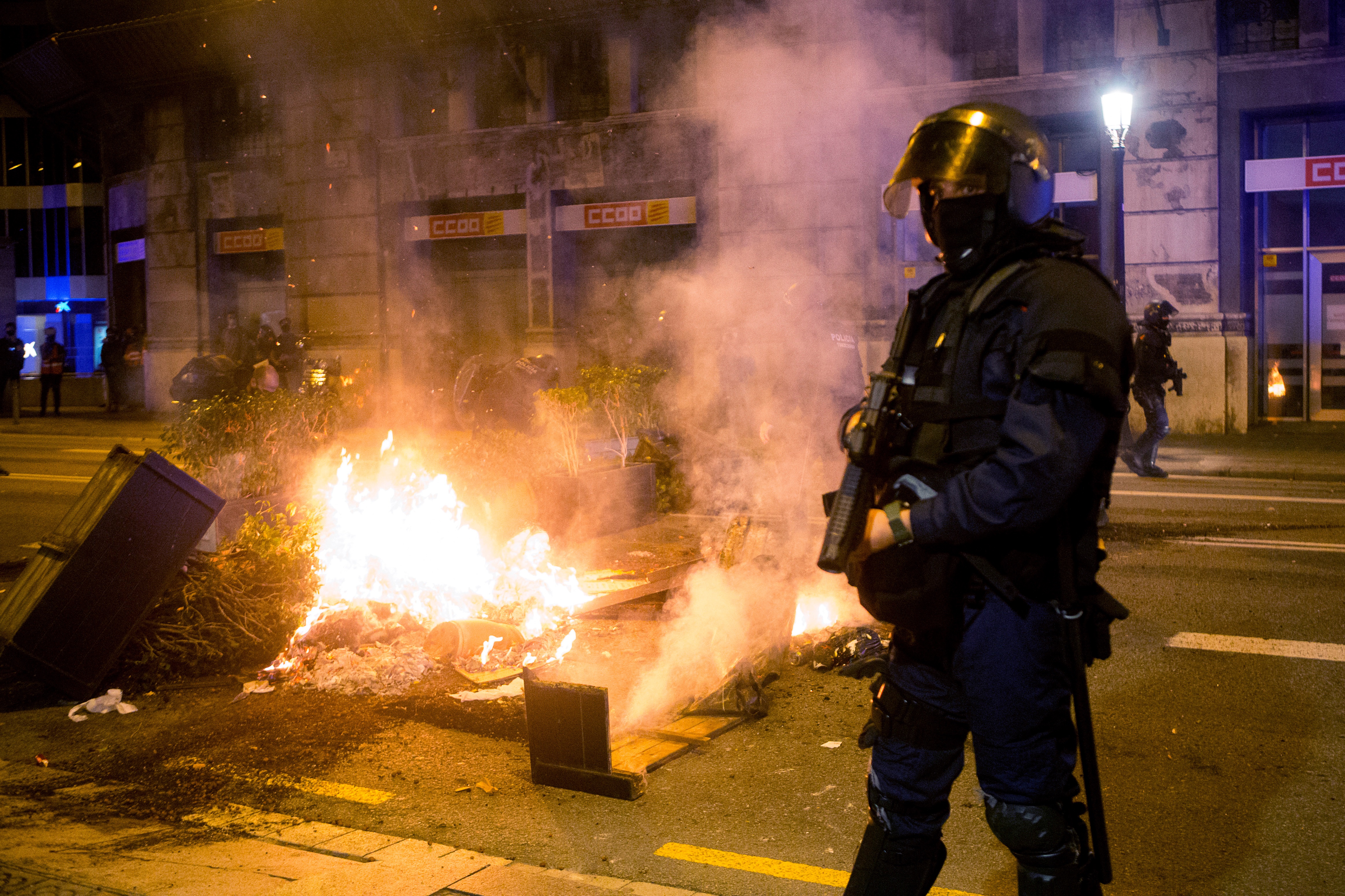 epa08786939 Mossos d'Esquadra agents stand guard as COVID-19 deniers burn urban furniture during a march to protest against the restrictions imposed to fight against the coronavirus pandemic, in Barcelona, Spain, 30 October 2020.  EPA-EFE/QUIQUE GARCIA