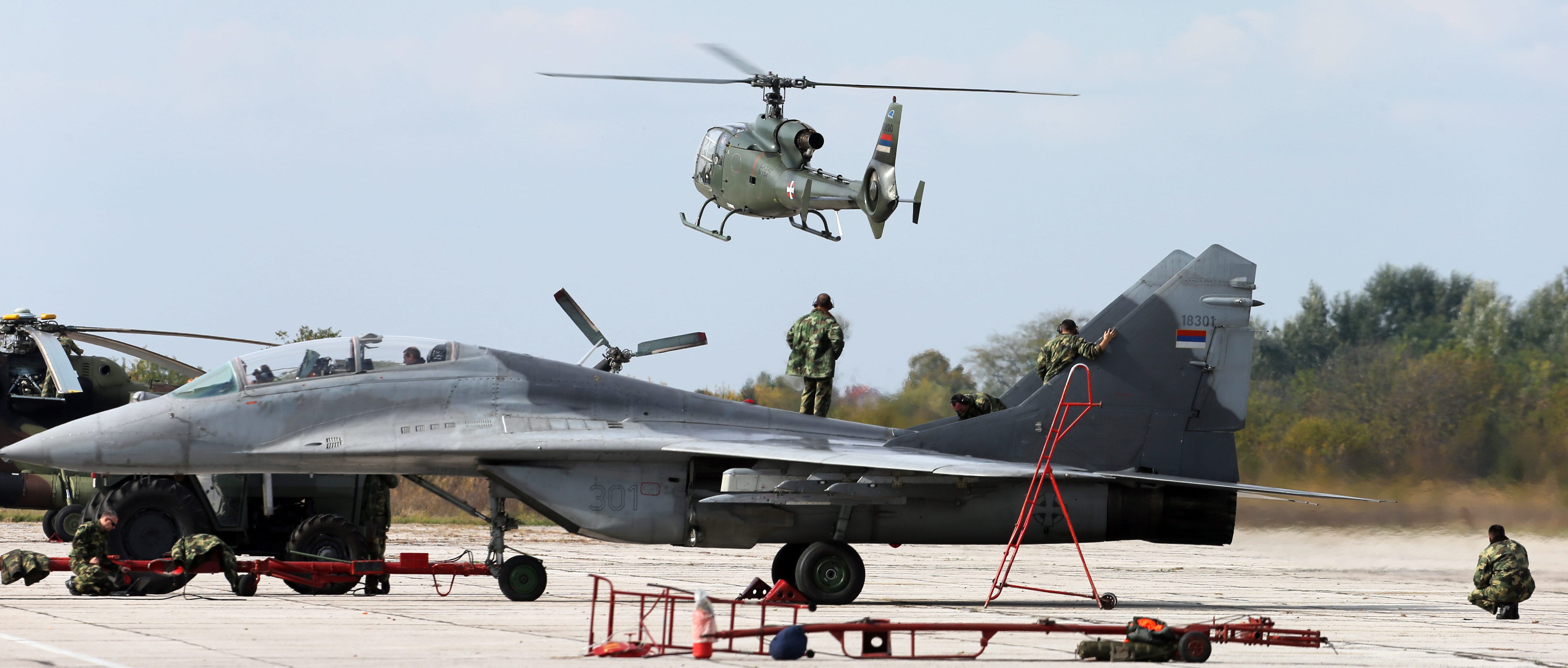 epa05583892 Serbian air force's AEROSPATIALE Gazelle (SOKO) SA-342 GAMA helicopter (top) hovers over MiG-29 jets during a tactical exercise at the military airport in Batajnica in Belgrade, Serbia, 13 October 2016.  EPA/KOCA SULEJMANOVIC