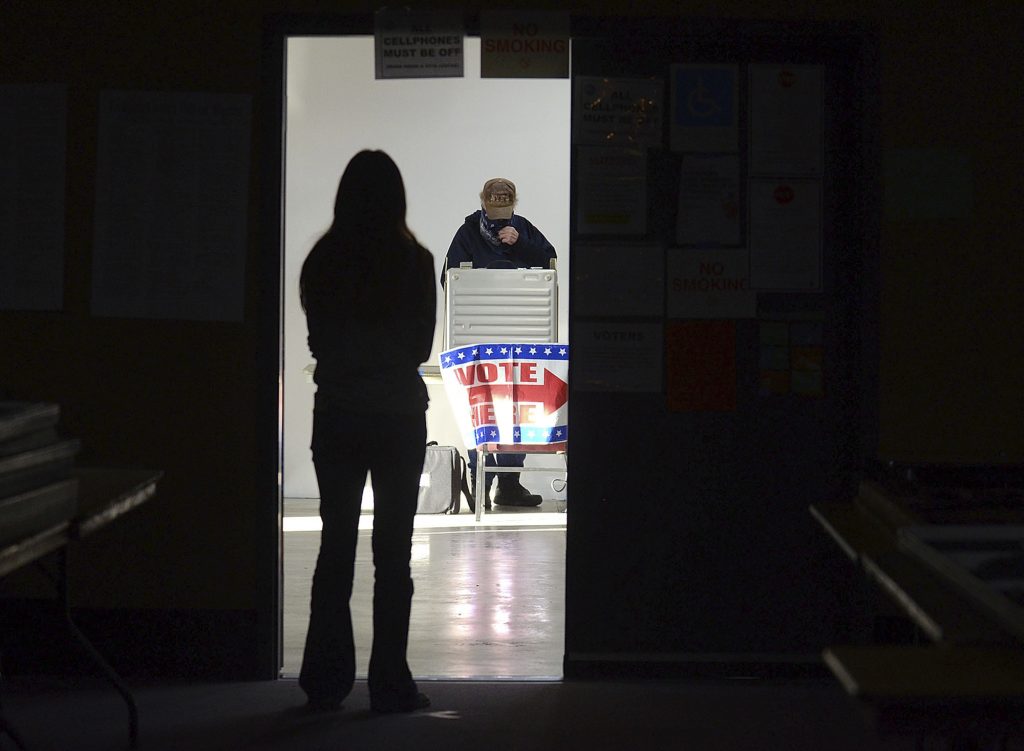 First-time voter Baylee Fidler, 19, waits in the doorway for a voting booth as Tom Davis, background, completes his ballot at the Boot City Opry near Terre Haute, Ind., on Tuesday, Nov. 3, 2020. (Joseph C. Garza/The Tribune-Star via AP)