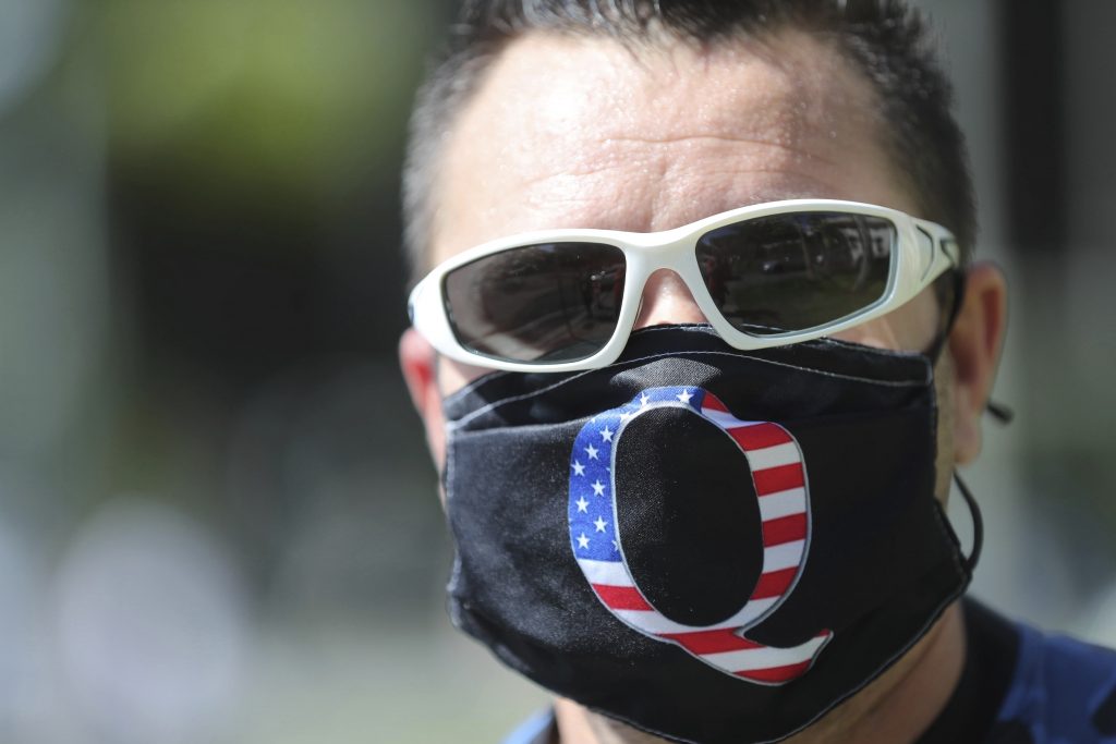 A man wearing a "Q" mask walks past city hall on Election Day, Tuesday, Nov. 3, 2020, in Honolulu. (AP Photo/Marco Garcia)