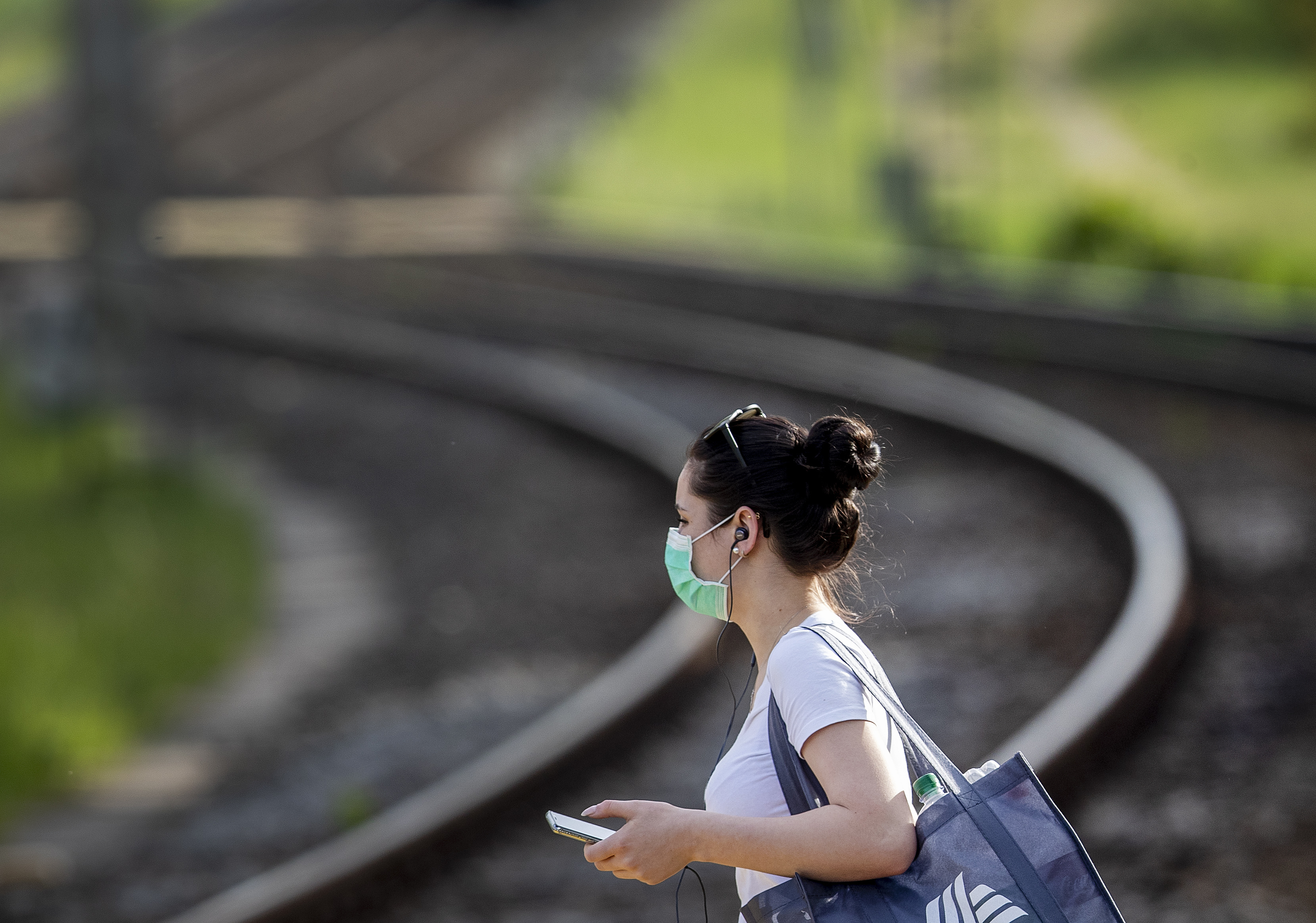 A woman wears a face mask as she goes to a bus stop in Frankfurt, Germany, Friday, May 8, 2020. To avoid the outspread of the coronavirus wearing a mask in busses and subway trains is mandatory. (AP Photo/Michael Probst)
