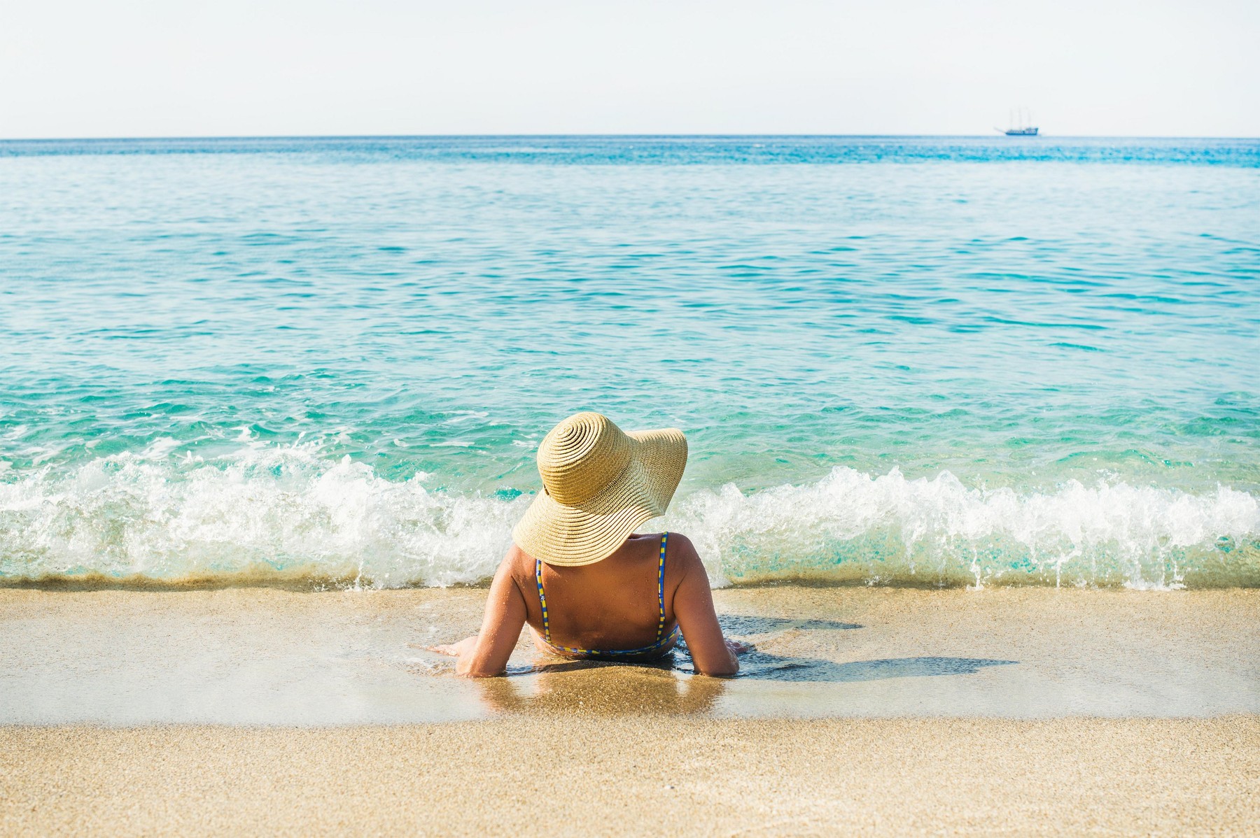 Woman lying on sand and enjoying clear blue sea waters