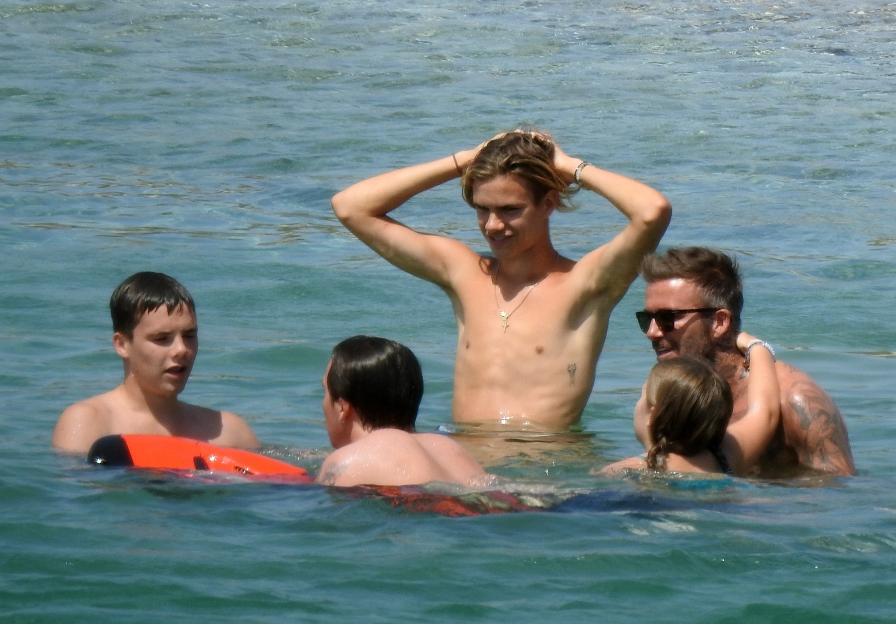 *PREMIUM EXCLUSIVE* David Beckham hugs daughter Harper, 9, as he takes a dip in a pair of Versace swim shorts on his Greek vacation.