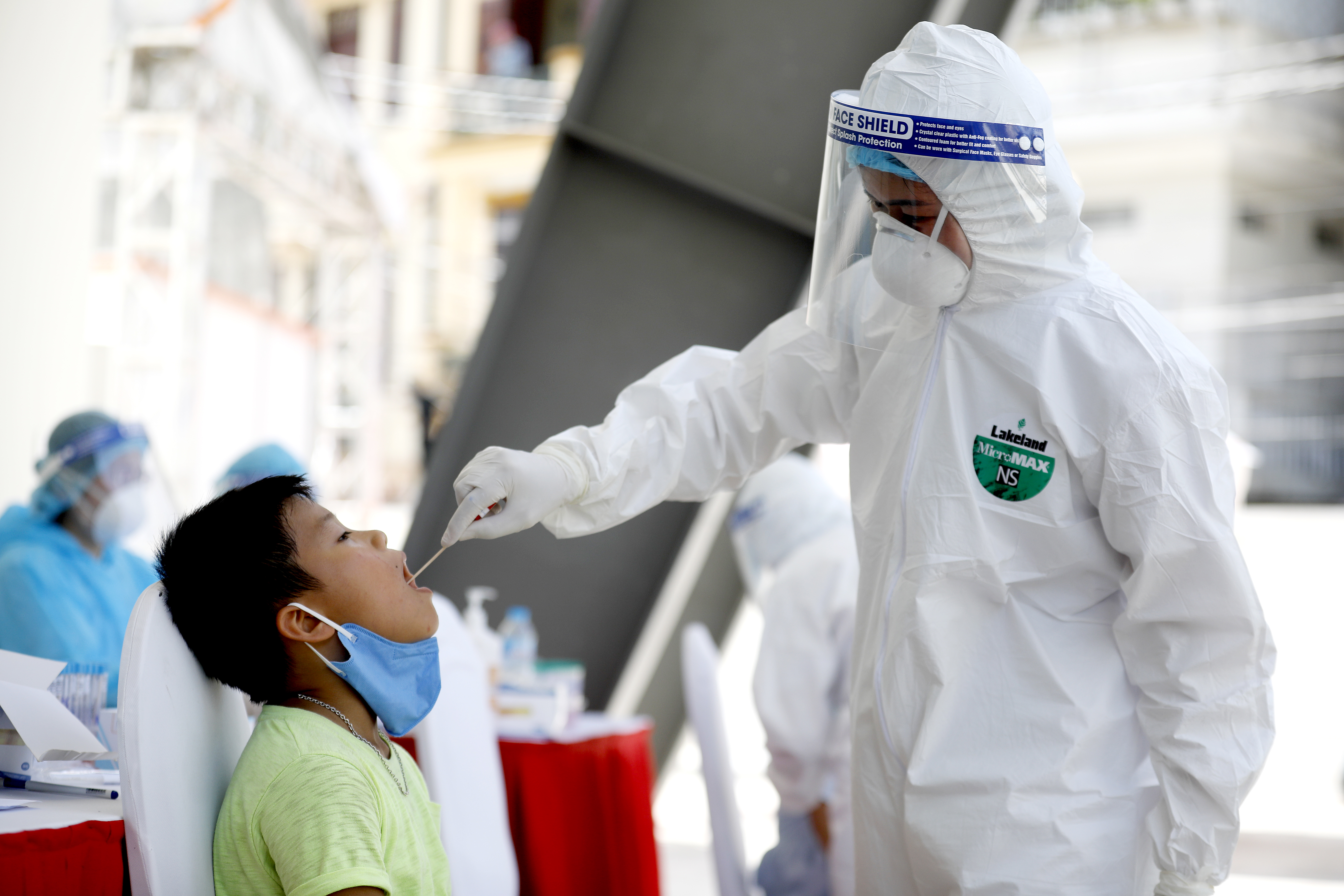 epa08596894 A boy has his swab sample collected by a health worker at a makeshift testing centre for coronavirus disease (COVID-19) in Hanoi, Vietnam 11 August 2020.  EPA-EFE/LUONG THAI LINH