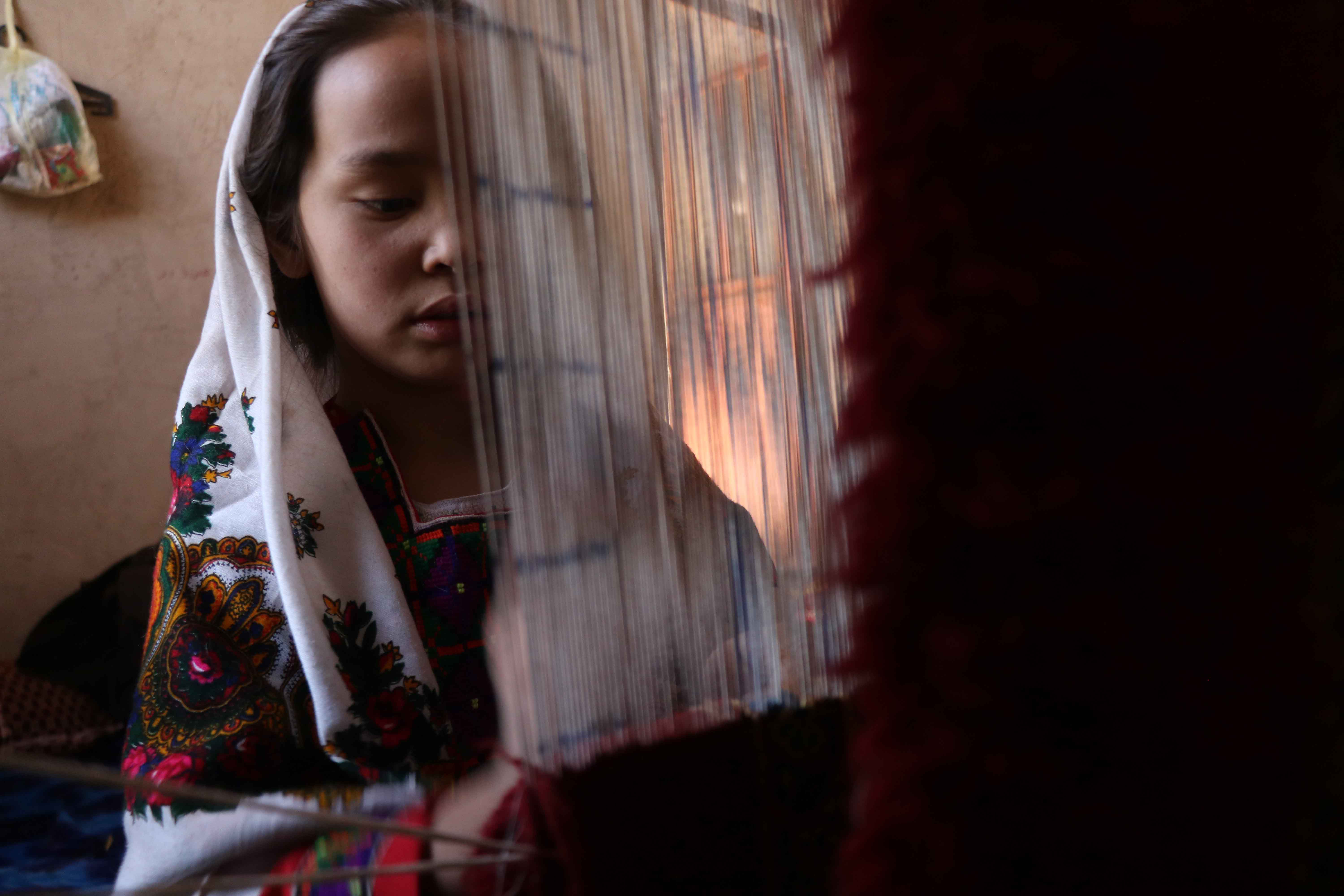 Afghan women work at a carpet loom in Herat
