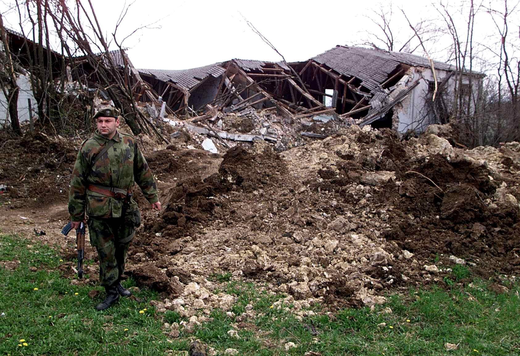 A Yugoslav soldier walks past a hole in the ground Wednesday 31 March 1999  reportedly caused by a NATO bomb dropped near the Yugoslav army barrack in Kragujevac on the first day of bombing.  EPA/SRDJAN SUKI