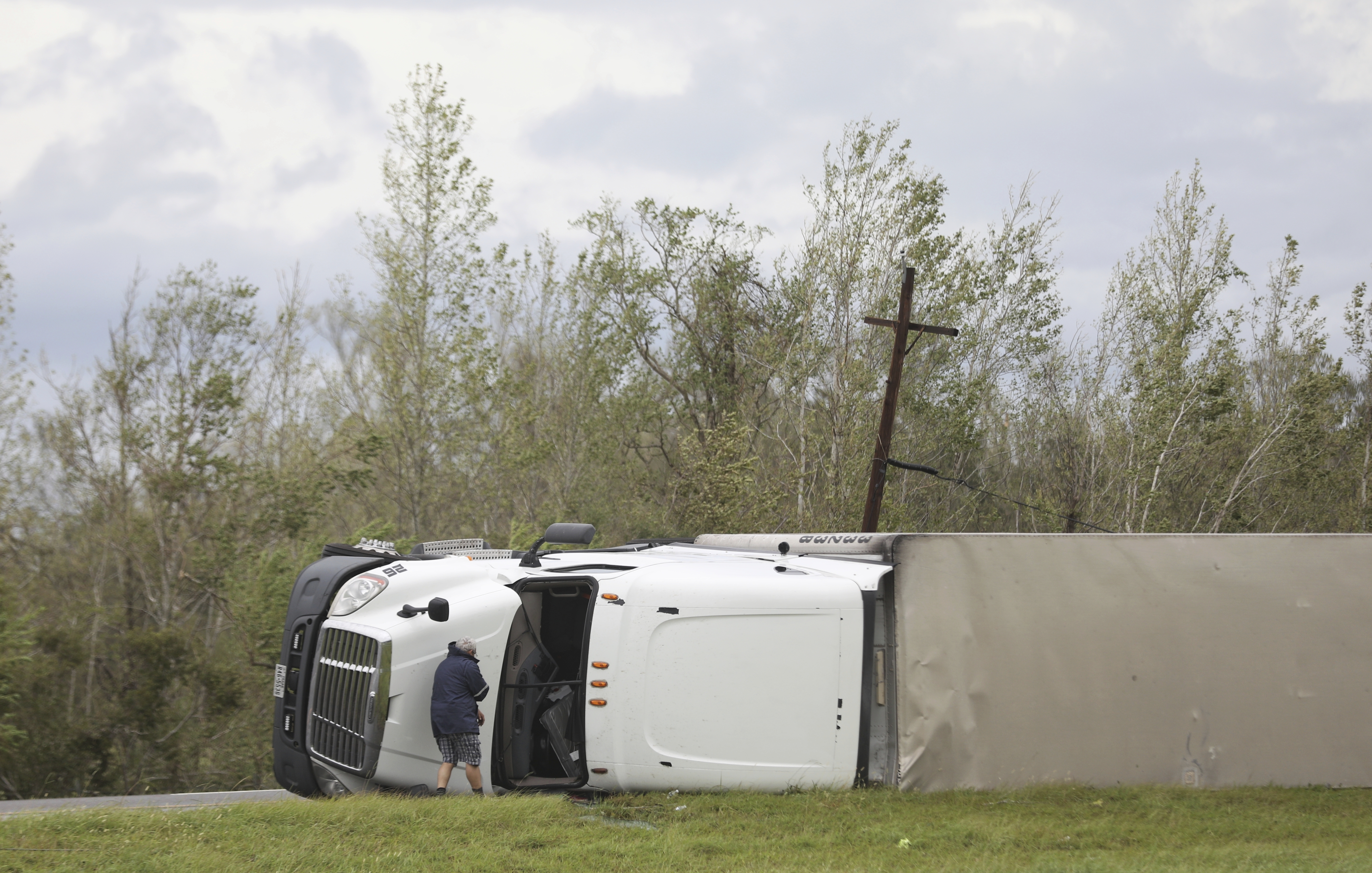 A man looks into an overturned 18-wheeler truck at daybreak after Hurricane Laura moved through the area Thursday, Aug. 27, 2020, near Sulphur, La. (Jon Shapley/Houston Chronicle via AP)