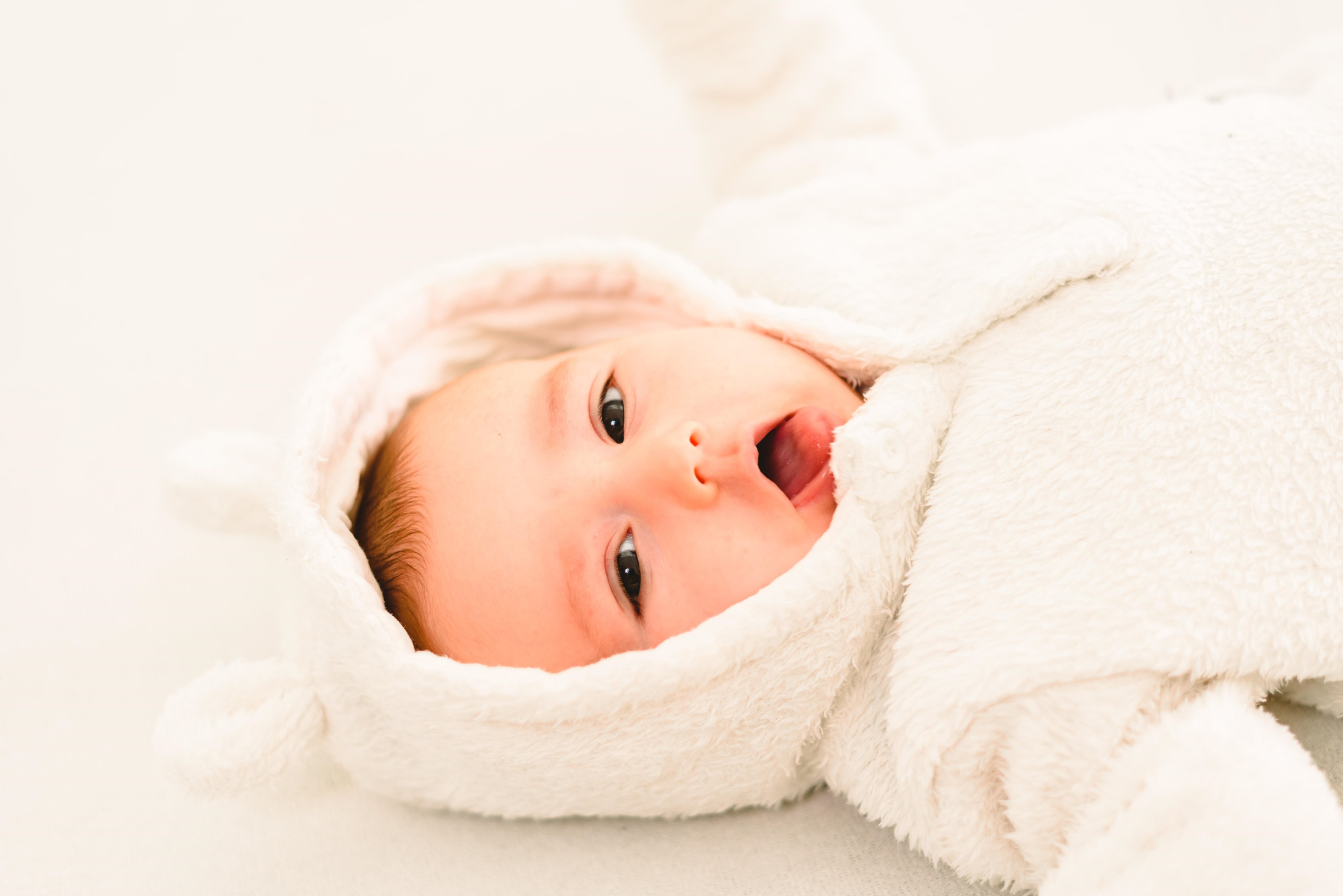 Newborn baby girl posed and playing with her tongue to talk, looking at camera