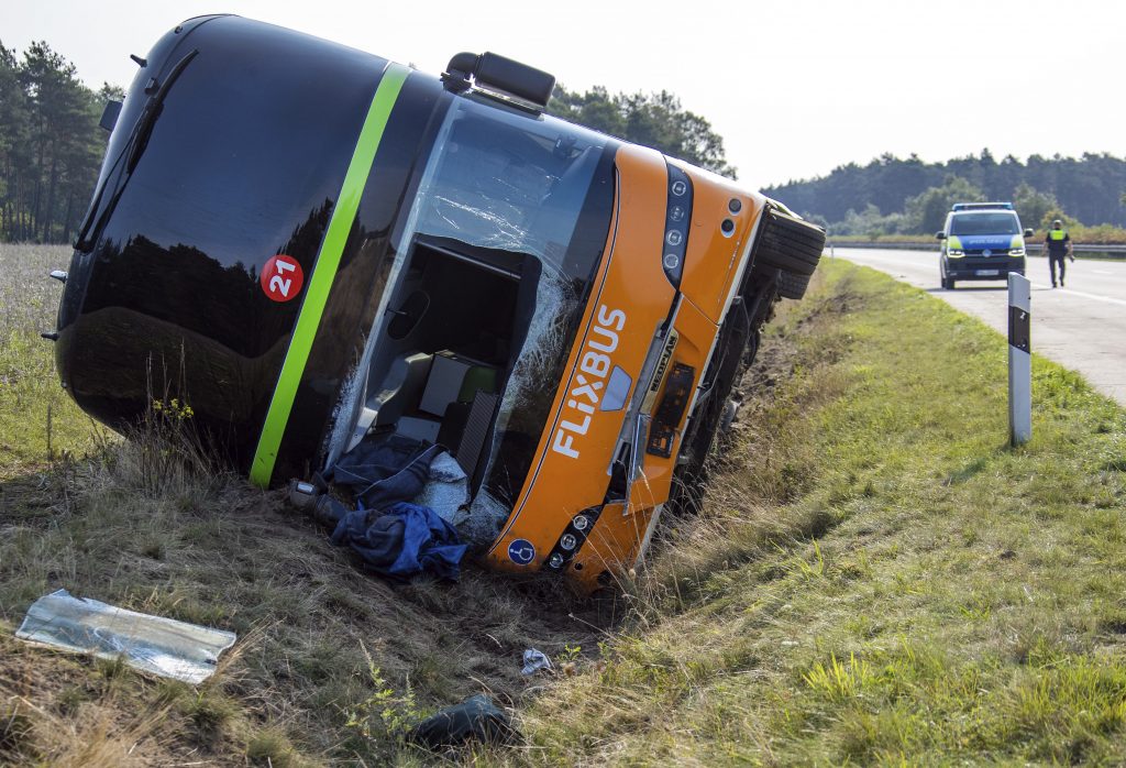 A a long-distance bus lies in the ditch along the A24 motorway in Woebbelin, northern Germany, Saturday, Sept. 12, 2020. According to police several people were injured in a long-distance bus accident early Saturday morning. (Jens Buettner/dpa via AP)