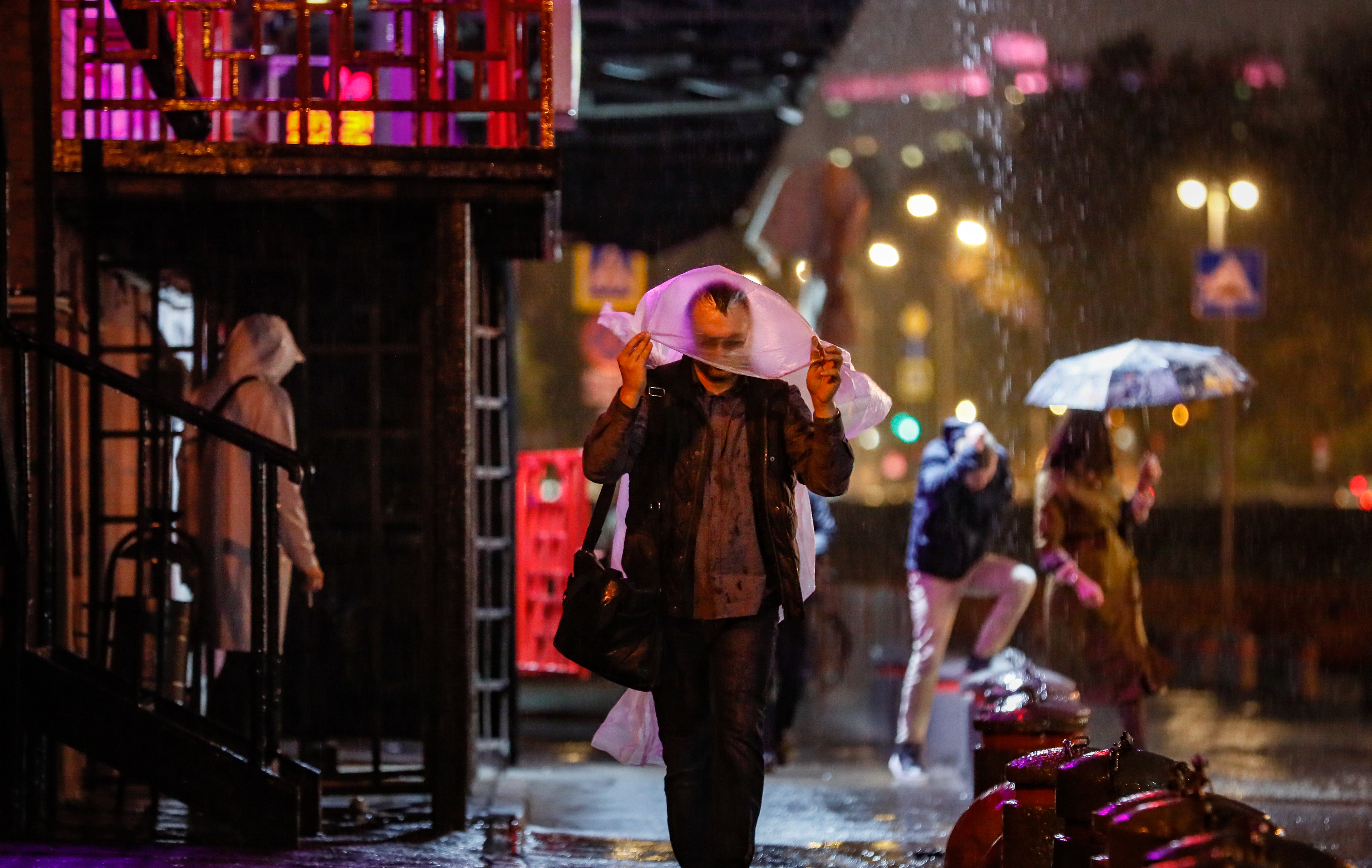 epa08677063 Russian people walk during heavy rain in Moscow, Russia 17 September 2020. Over two hours a third of the monthly average rainfall fell in Moscow.  EPA-EFE/YURI KOCHETKOV