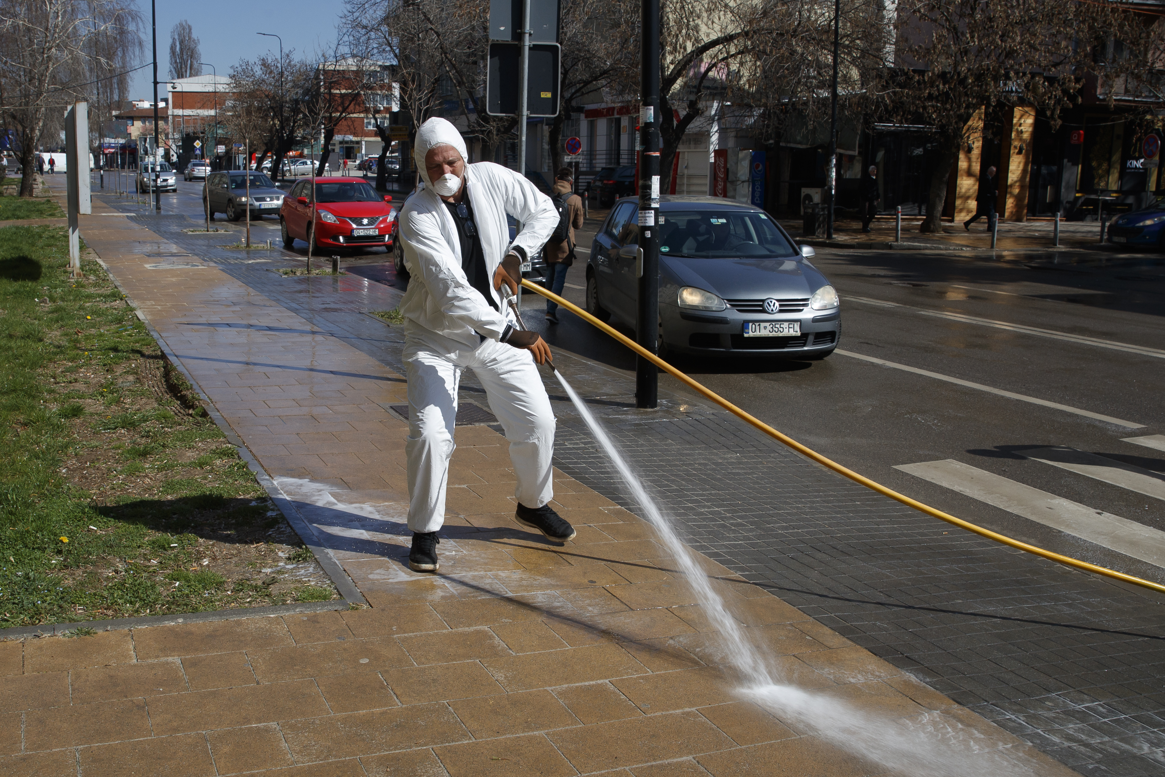 epa08300159 An employee wearing a protective body suit cleans the streets to prevent spread of the coronavirus SARS-CoV-2, which causes the COVID-19 disease, in Pristina, Kosovo, 17 March 2020.  EPA-EFE/VALDRIN XHEMAJ