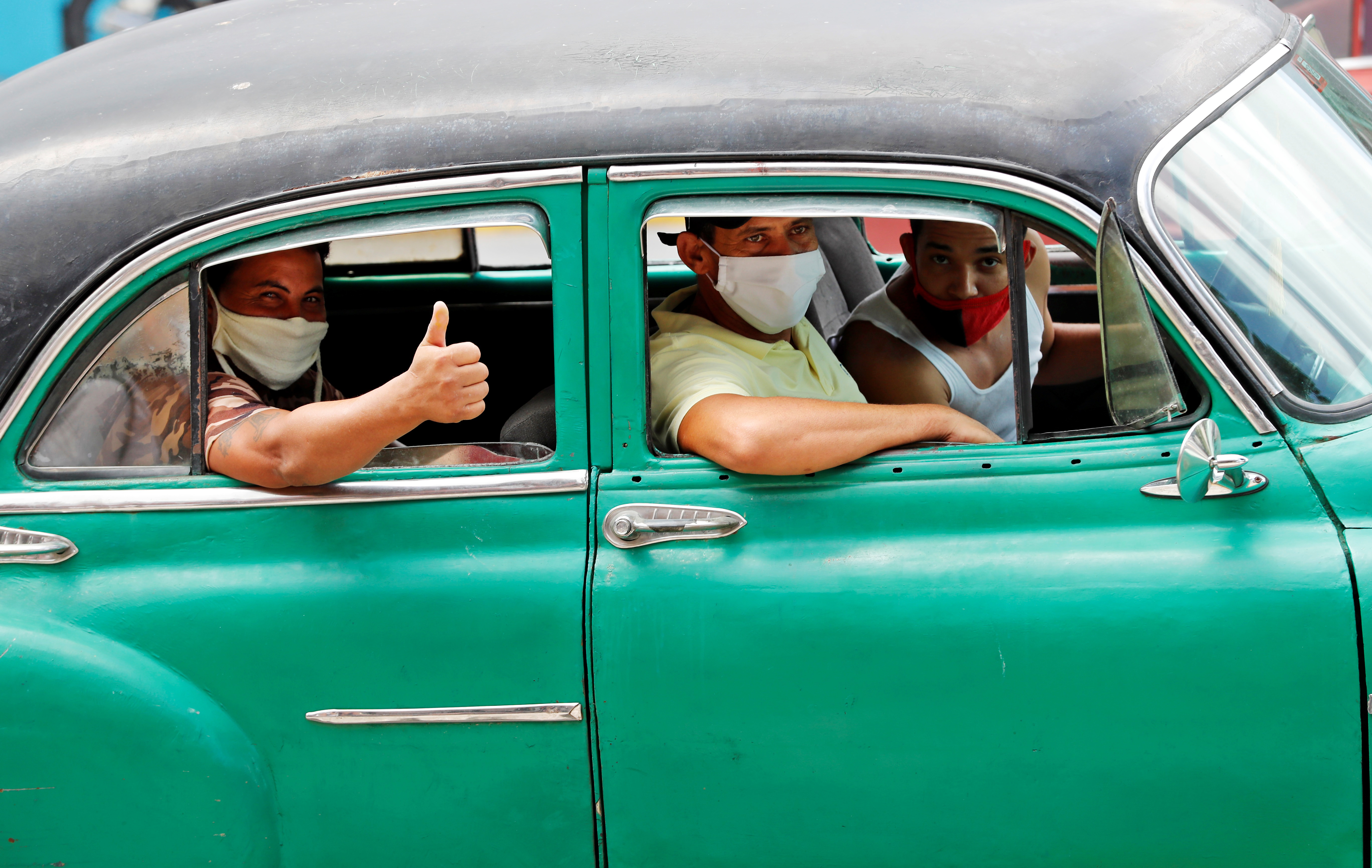 epaselect epa08518546 Men wear masks inside a classic car, in Havana, Cuba, 30 June 2020.  EPA-EFE/Ernesto Mastrascusa