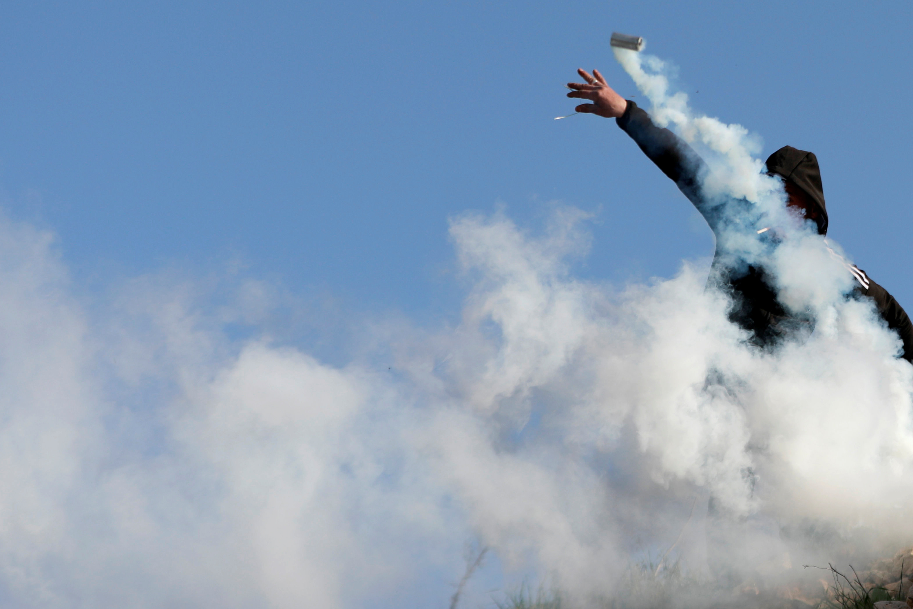 A Palestinian demonstrator hurls a tear gas canister fired by Israeli forces during a protest against Israeli settlements, near the town of Beita in the Israeli-occupied West Bank March 11, 2020. REUTERS/Mohamad Torokman - RC2KHF9XK0RK