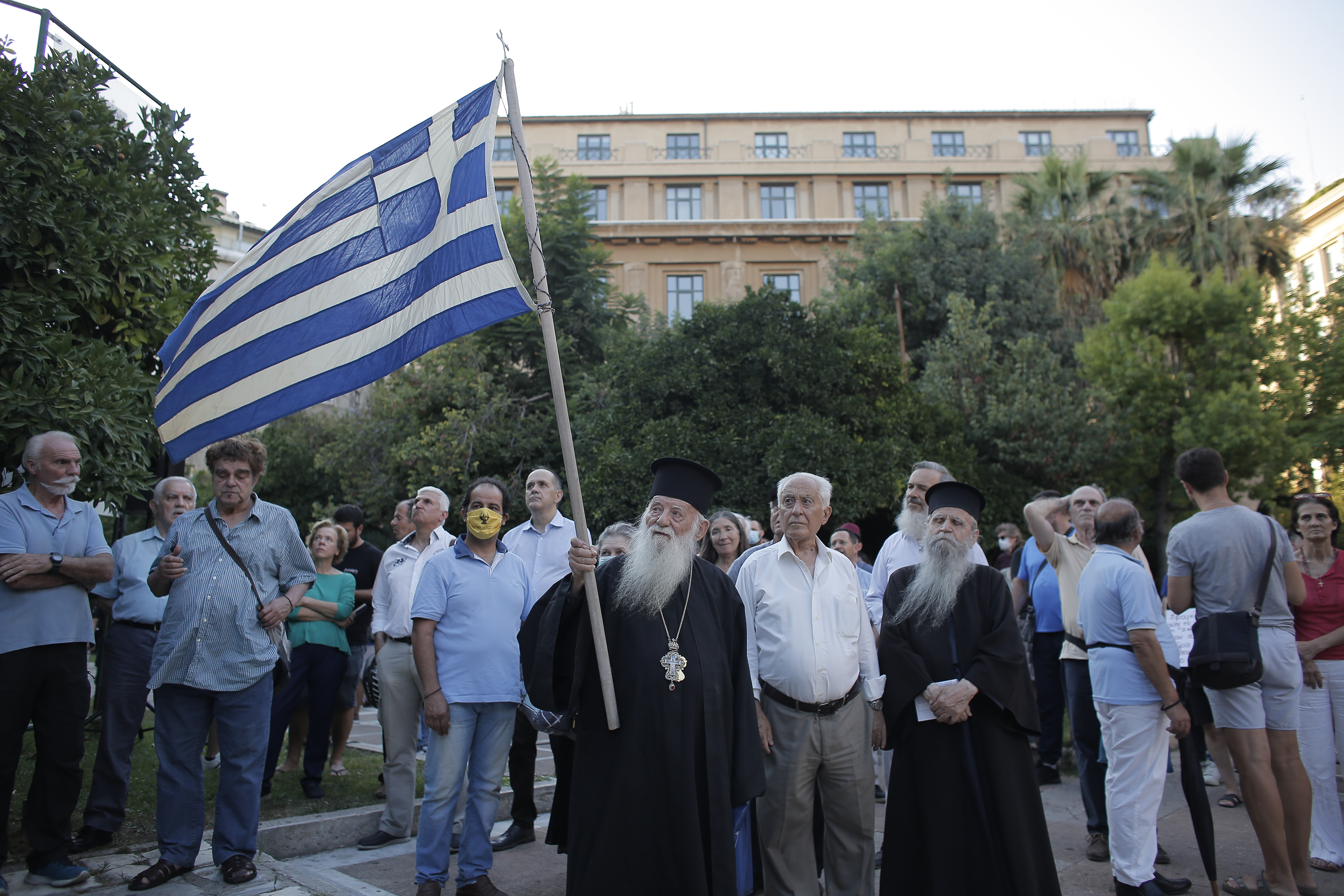 epa08564799 A Greek Orthodox priest holds a Greek National flag during a rally against the decision of Turkish Government to convert Hagia Sophia into a mosque, in Athens, Greece, 24 July 2020.  EPA-EFE/KOSTAS TSIRONIS