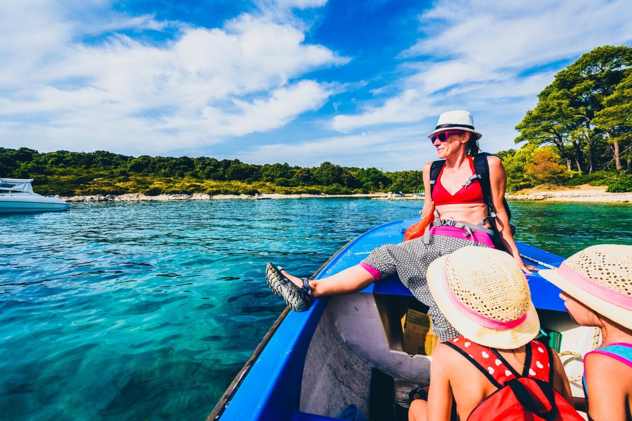 Mother and daughters in a boat on the sea. Family is riding with a boat with mother on the front and children in the middle. Young attractive mother i