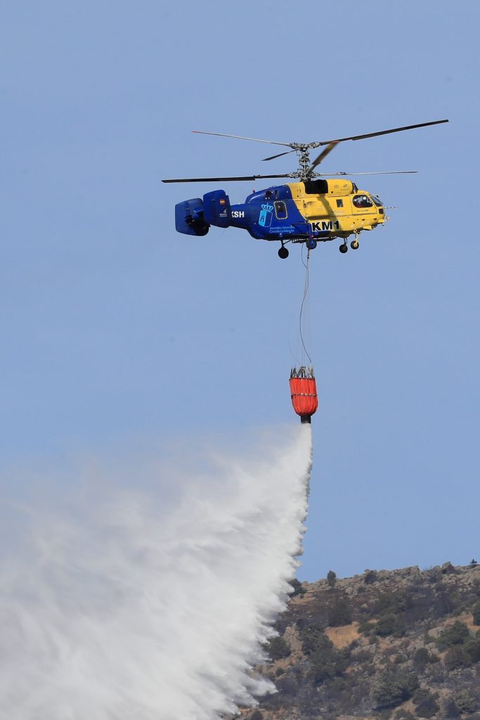 epa08581495 Firefighters use a helicopter to put out hot spots from a fire burning in the village of Robledo de Chavela, Madrid, Spain, 03 August 2020. According to reports, the fire has burnt some 800 hectares of land.  EPA-EFE/FERNANDO ALVARADO
