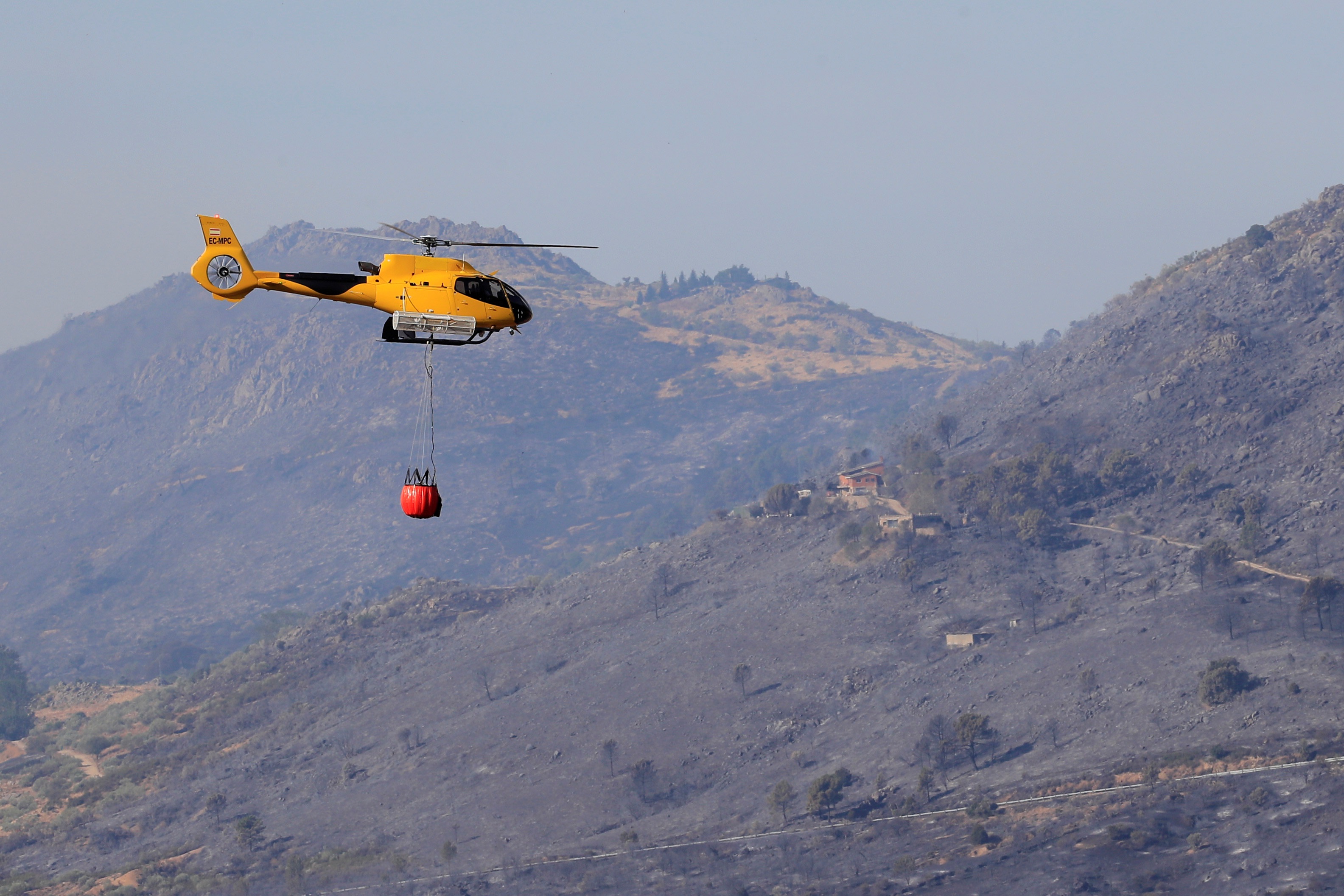 epa08581496 Firefighters use a helicopter to put out hot spots from a fire burning in the village of Robledo de Chavela, Madrid, Spain, 03 August 2020. According to reports, the fire has burnt some 800 hectares of land.  EPA-EFE/FERNANDO ALVARADO