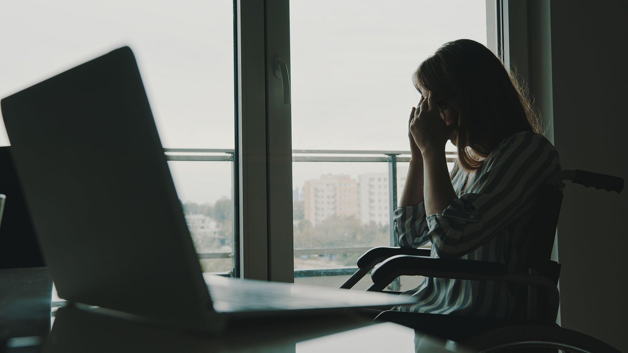 depressed young disabled woman near the window having a headache. High quality photo