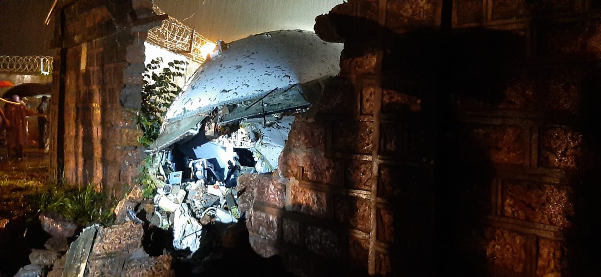 A part of the Air India Express flight is seen through a broken wall after it skidded off a runway while landing at the airport in Kozhikode, Kerala state, India, Friday, Aug. 7, 2020. (AP Photo)