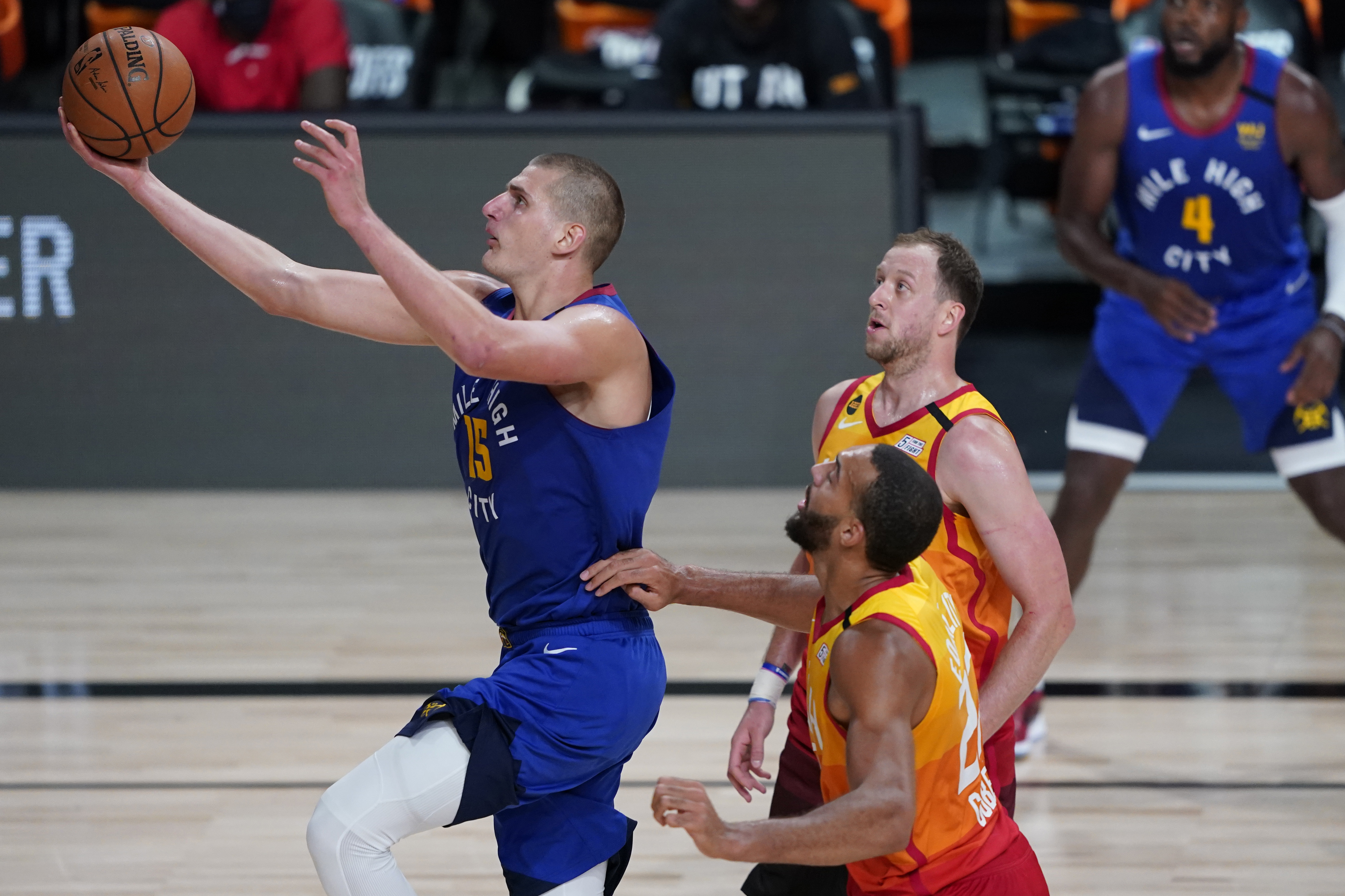 Denver Nuggets' Nikola Jokic (15) shoots as Utah Jazz's Joe Ingles, right, and Rudy Gobert, center, defend during the second half of an NBA basketball first round playoff game Friday, Aug. 21, 2020, in Lake Buena Vista, Fla. (AP Photo/Ashley Landis, Pool)