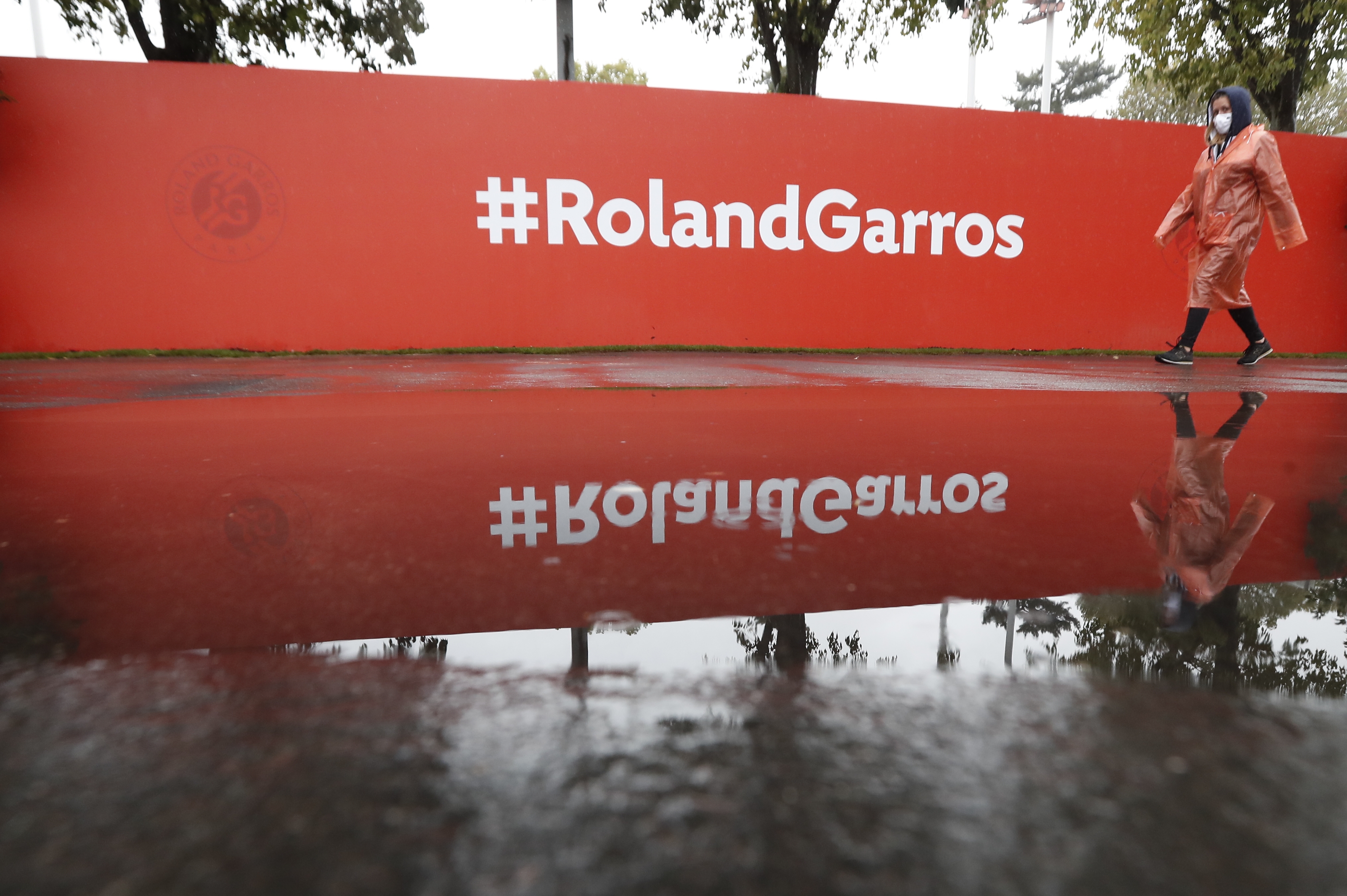 epa08703182 A woman wearing a face mask walks as rain delays play during the French Open tennis tournament at Roland ?Garros in Paris, France, 28  September 2020.  EPA-EFE/IAN LANGSDON