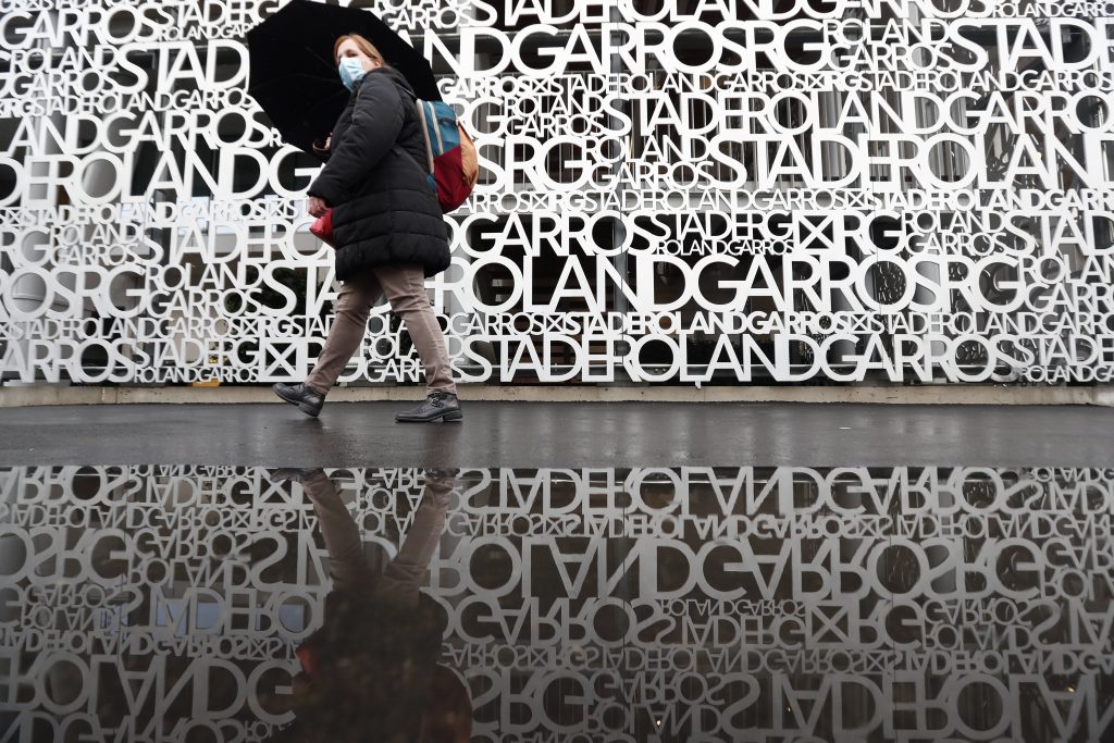 epaselect epa08703158 A woman wearing a face mask walks with an umbrella as rain delays play during the French Open tennis tournament at Roland ?Garros in Paris, France, 28  September 2020.  EPA-EFE/IAN LANGSDON