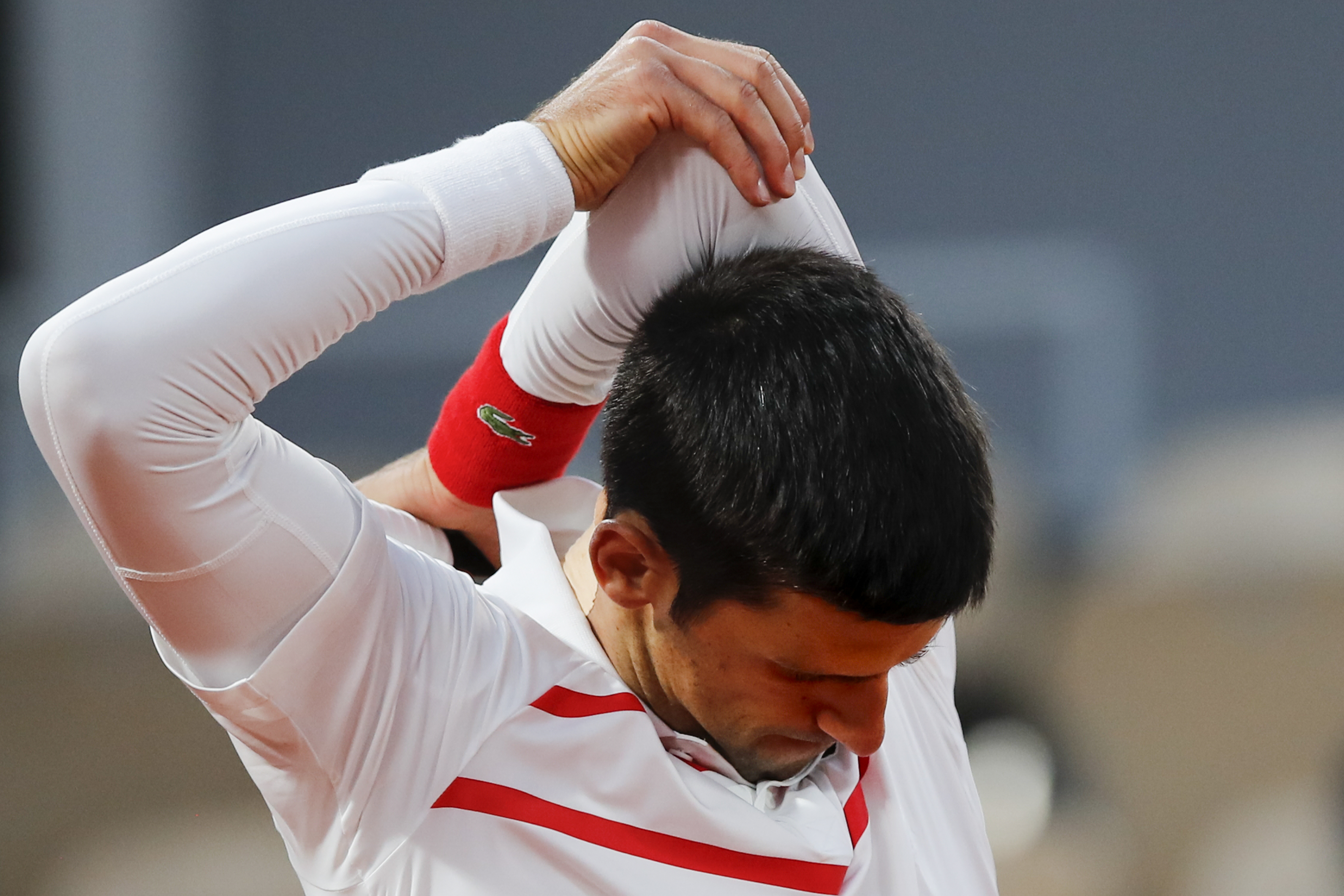 Serbia's Novak Djokovic stretches his left arm in the quarterfinal match of the French Open tennis tournament against Spain's Pablo Carreno Busta at the Roland Garros stadium in Paris, France, Wednesday, Oct. 7, 2020. (AP Photo/Christophe Ena)