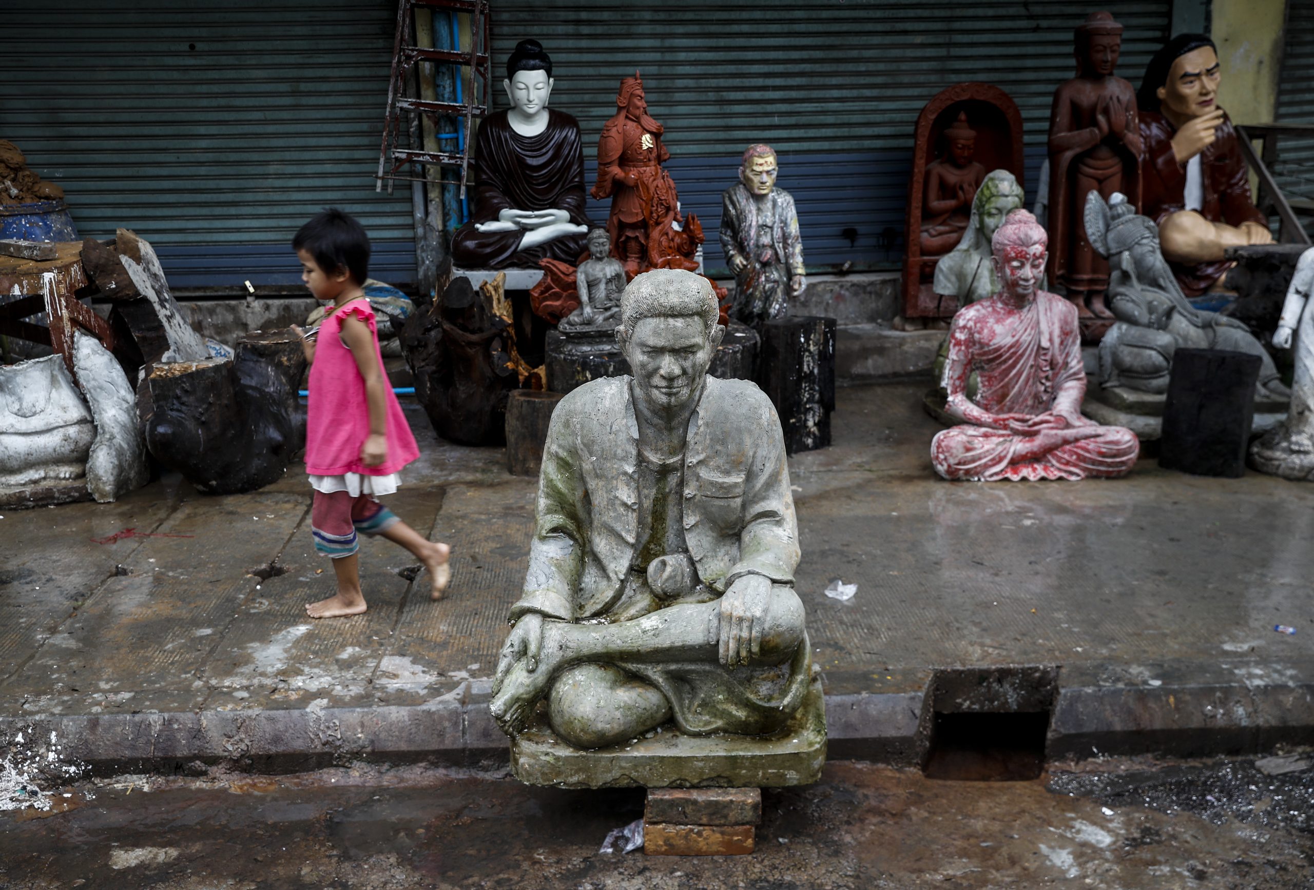 epaselect epa08478476 A Myanmar girl walks near sculptures of religious figures piled up at a street side near Shwedagon pagoda in Yangon, Myanmar, 11 June 2020.  EPA-EFE/LYNN BO BO