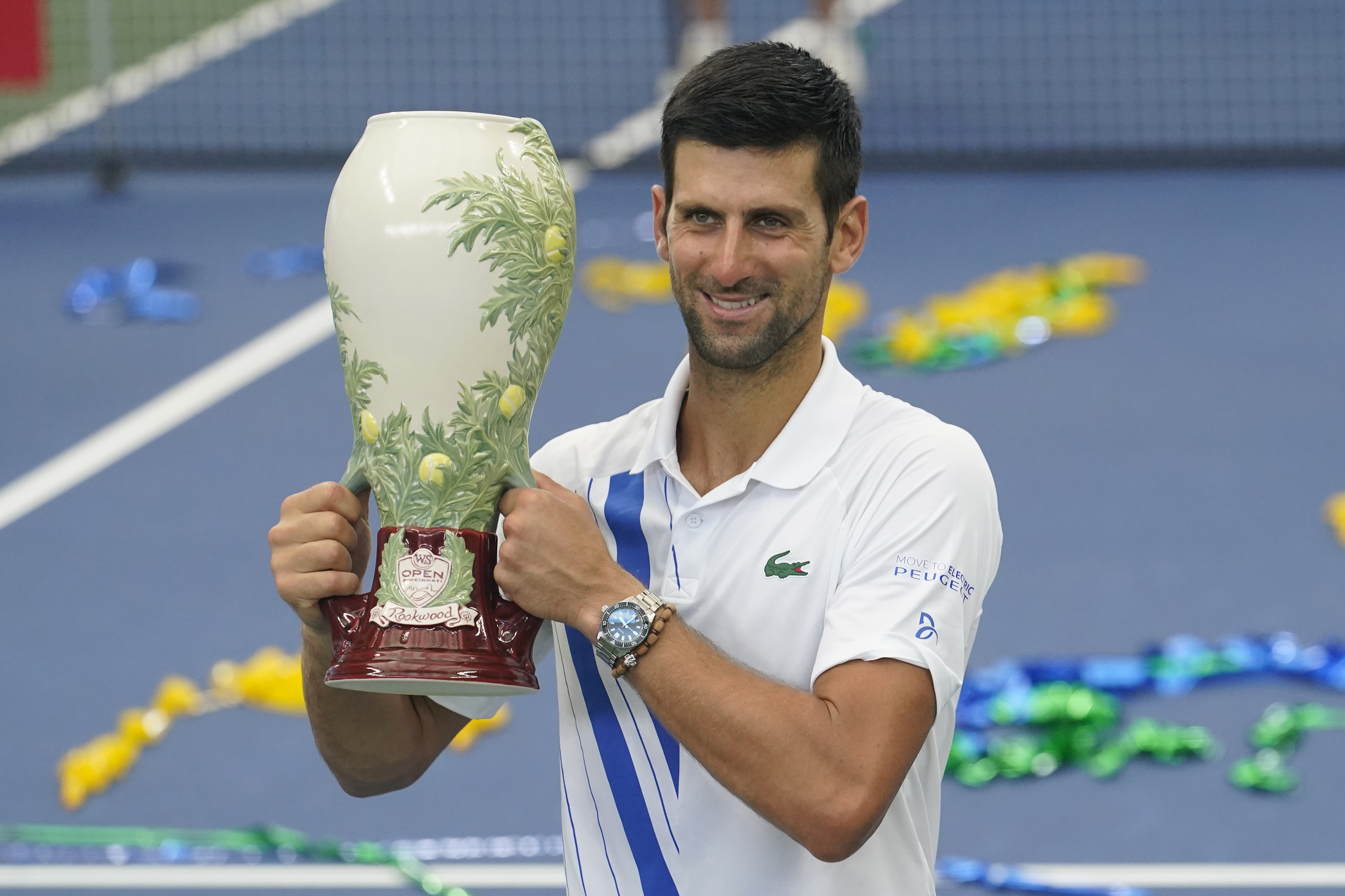 Novak Djokovic, of Serbia, front, holds his winning trophy after winning his match with Milos Raonic, of Canada, at the Western &amp; Southern Open tennis tournament Saturday, Aug. 29, 2020, in New York. (AP Photo/Frank Franklin II)