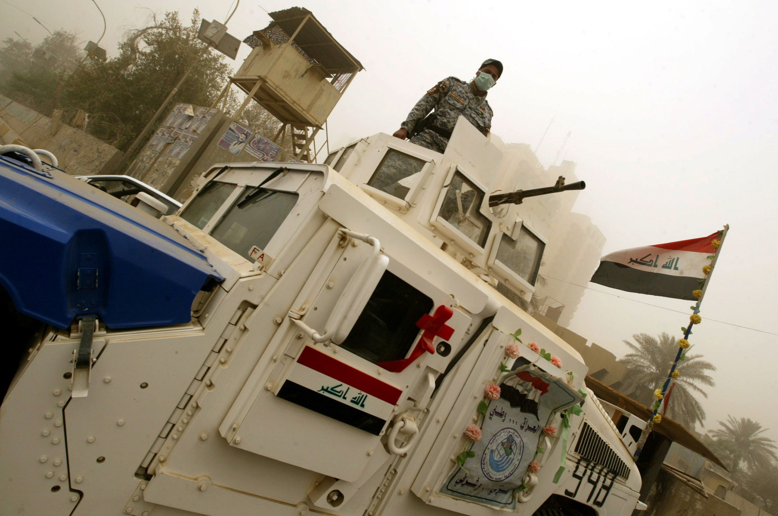 An Iraqi policeman wears a surgical  mask to protect himself from a sand storm